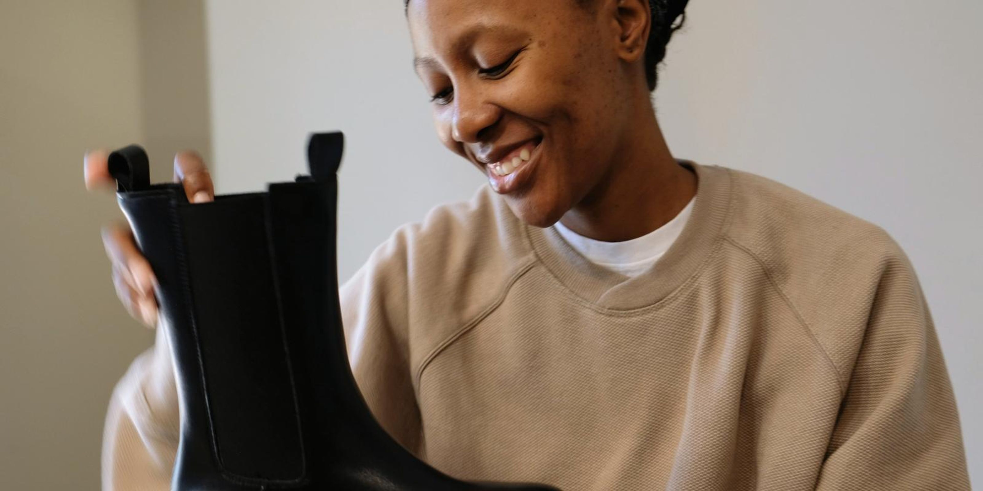 Frame of a smiling woman unboxing a pair of black chunky boots
