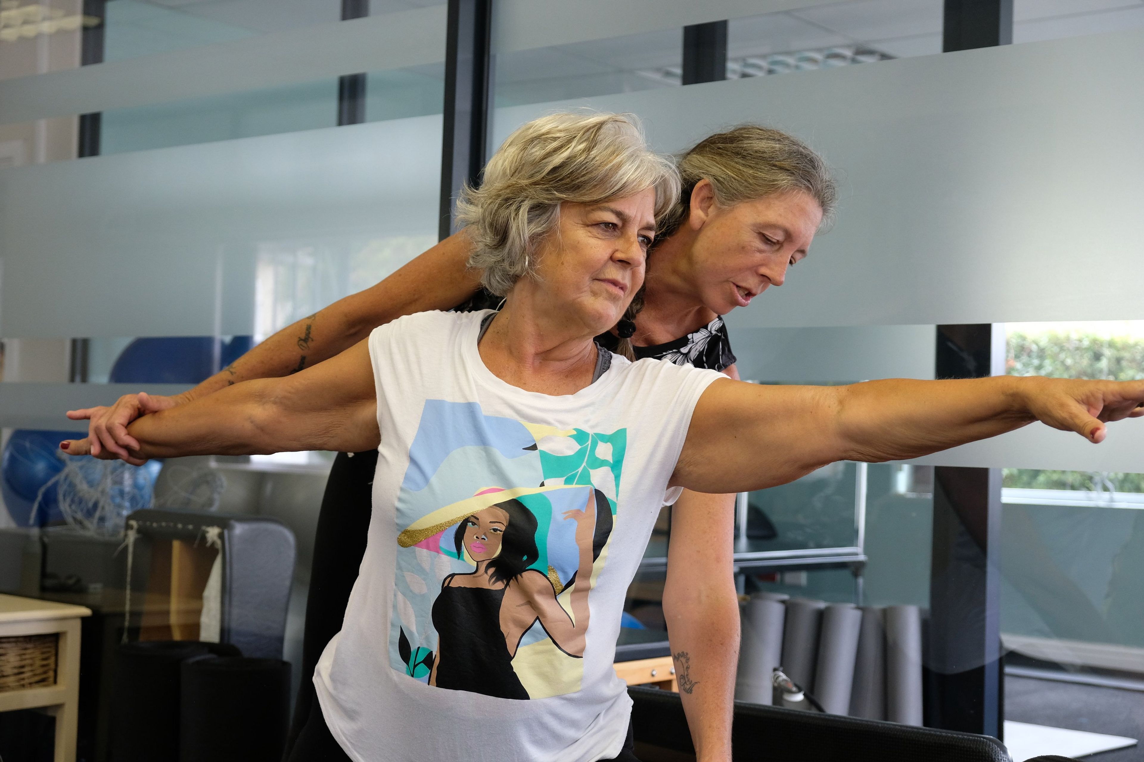 Two instructors working with a client who holds her arms out wide in a balance exercise