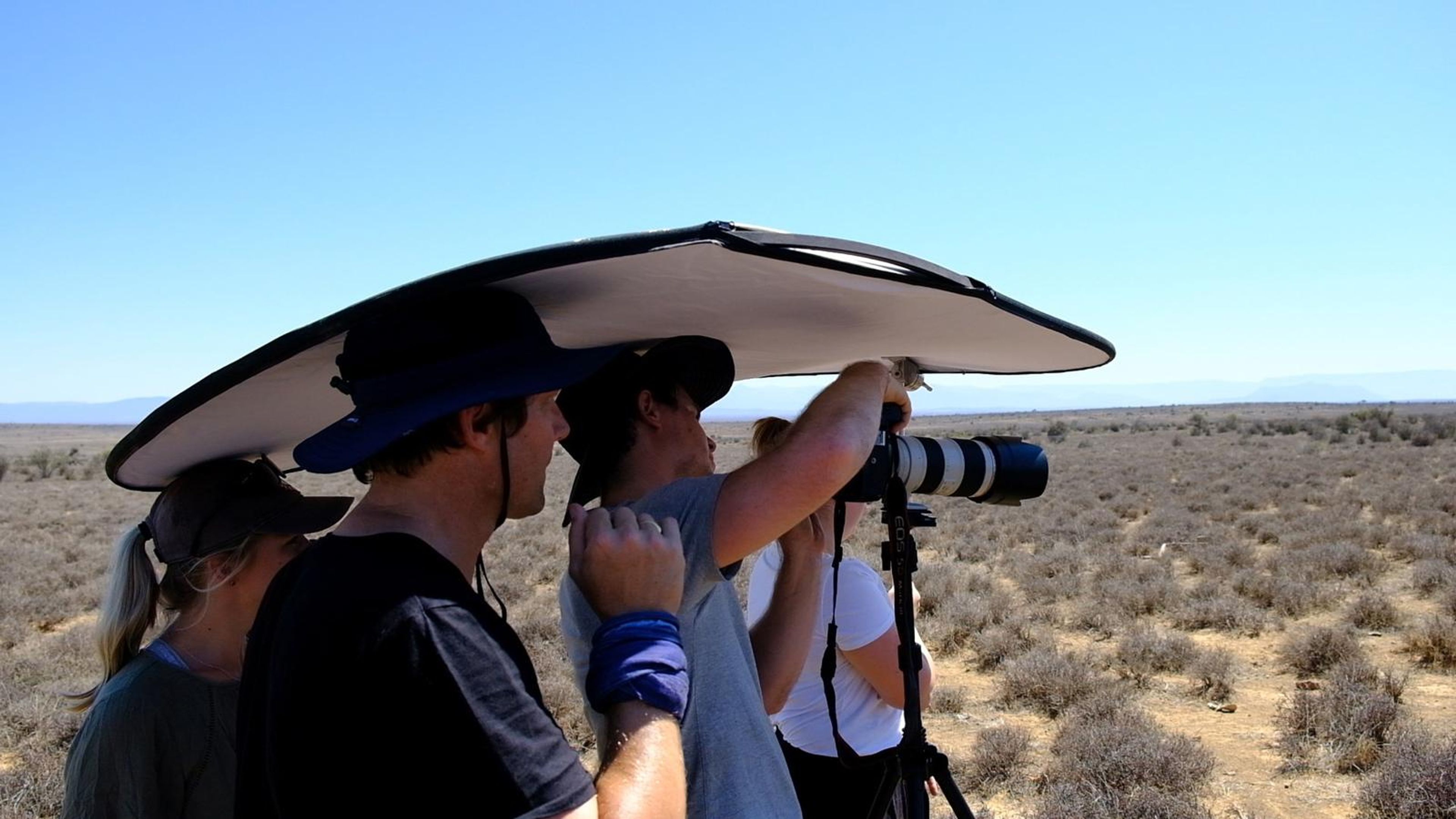Photographer shooting under a large diffuser while the model poses
