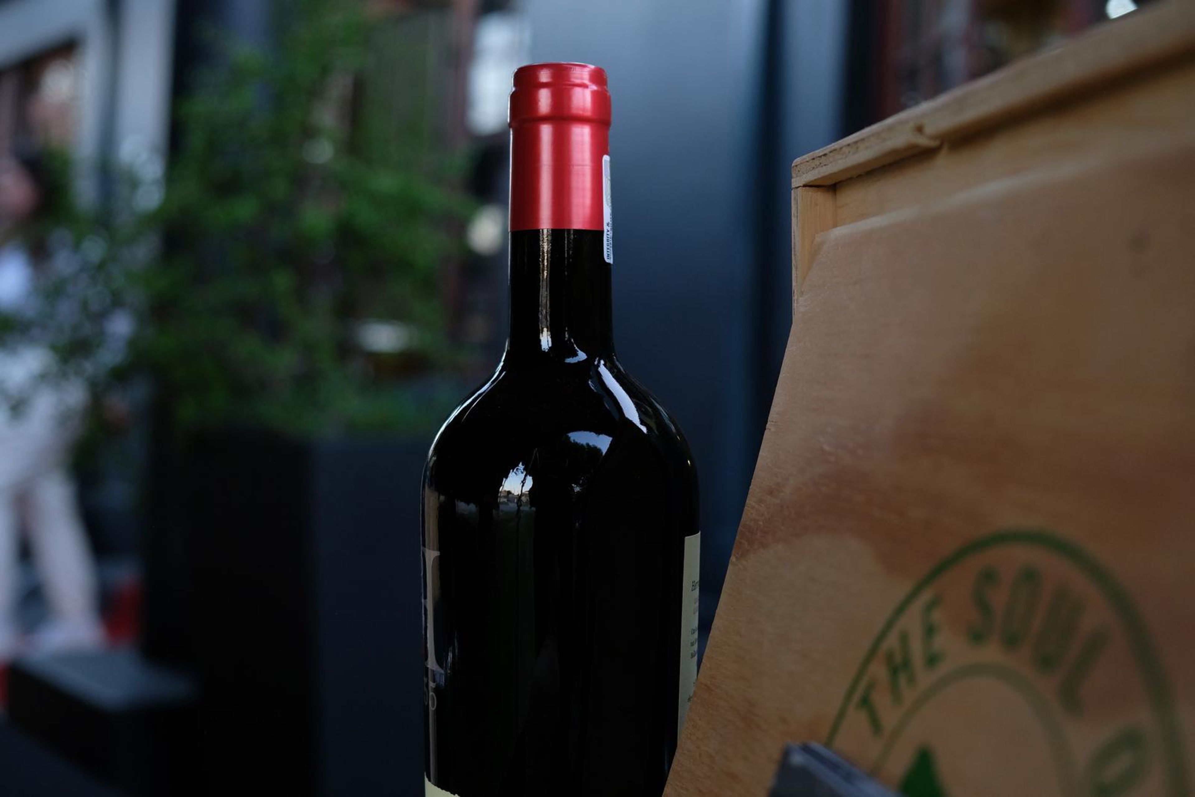 Close-up of a bottle of red wine beside a wooden Soul of the Land sign