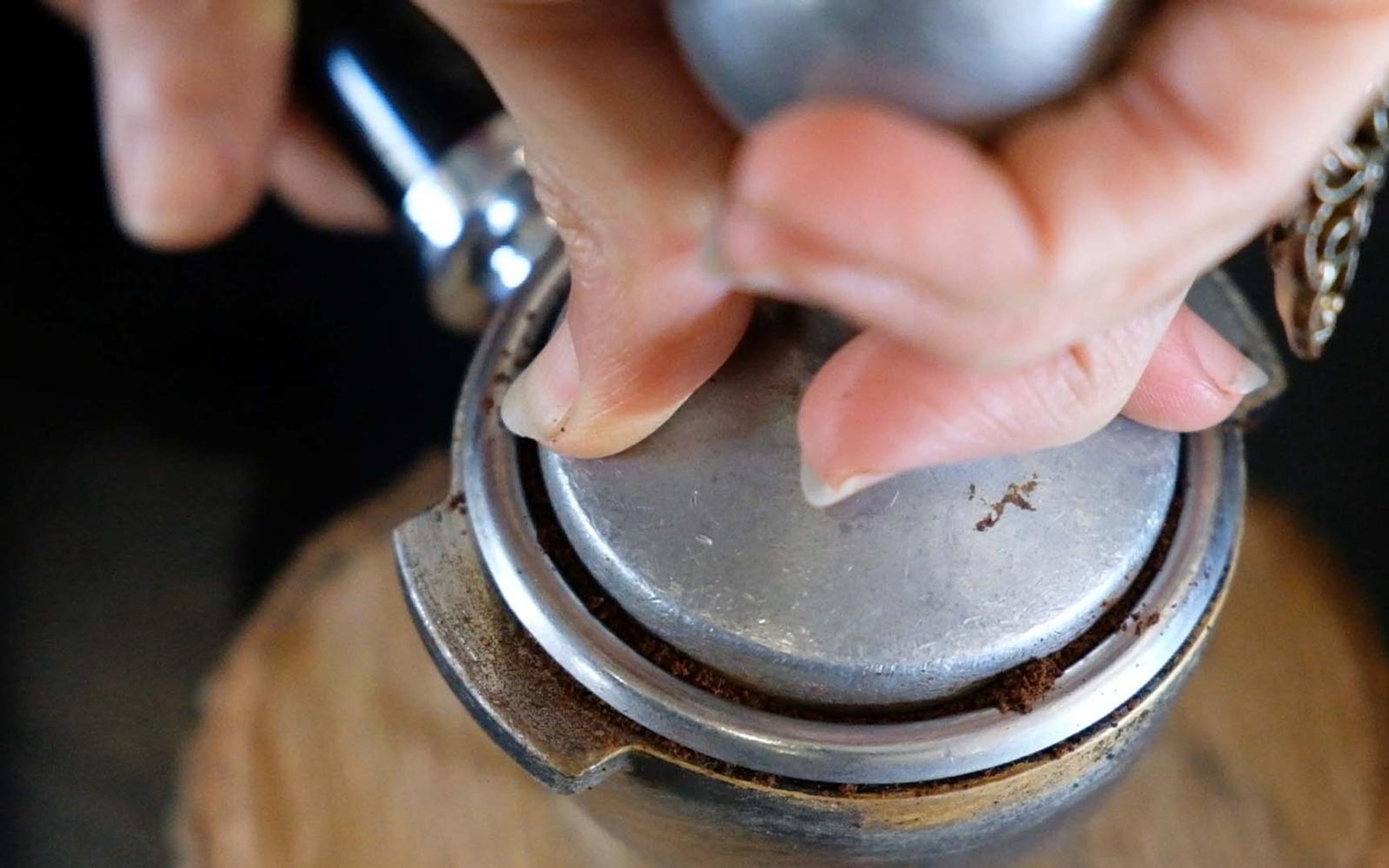 Close view of hands tamping ground coffee into a portafilter