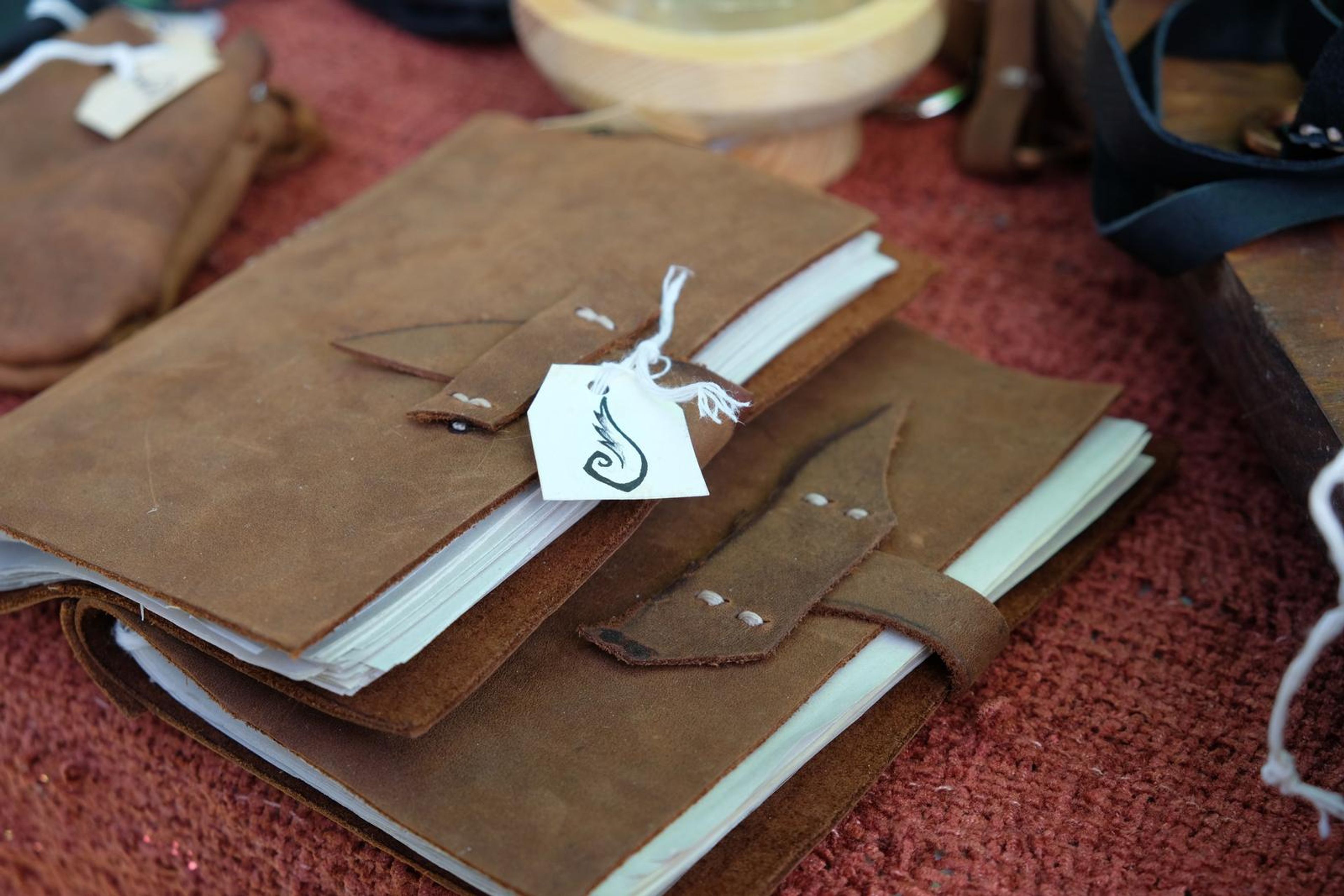 Handmade tan leather journal with a strap closure and tag