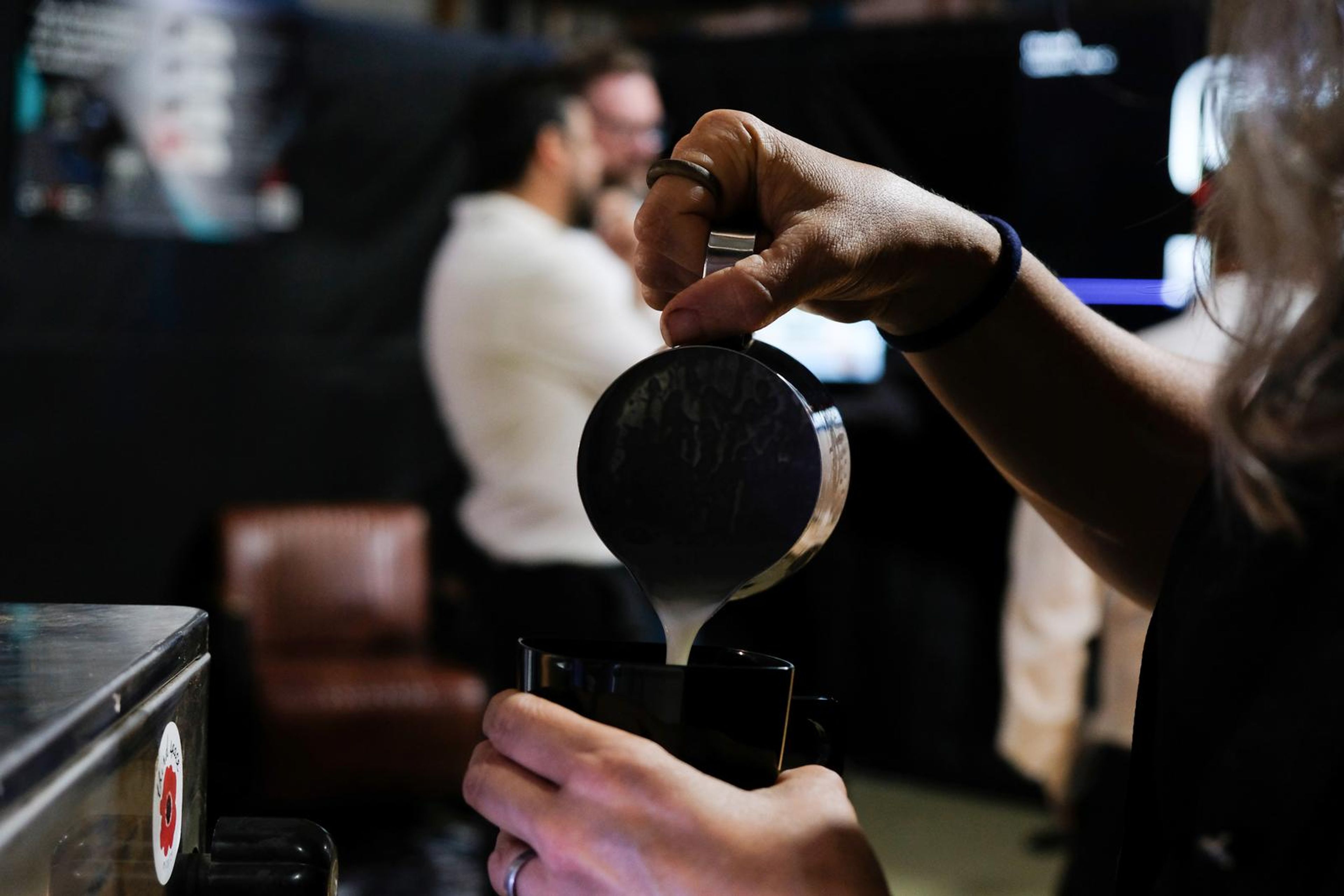Barista pouring steamed milk into a cup at the stall