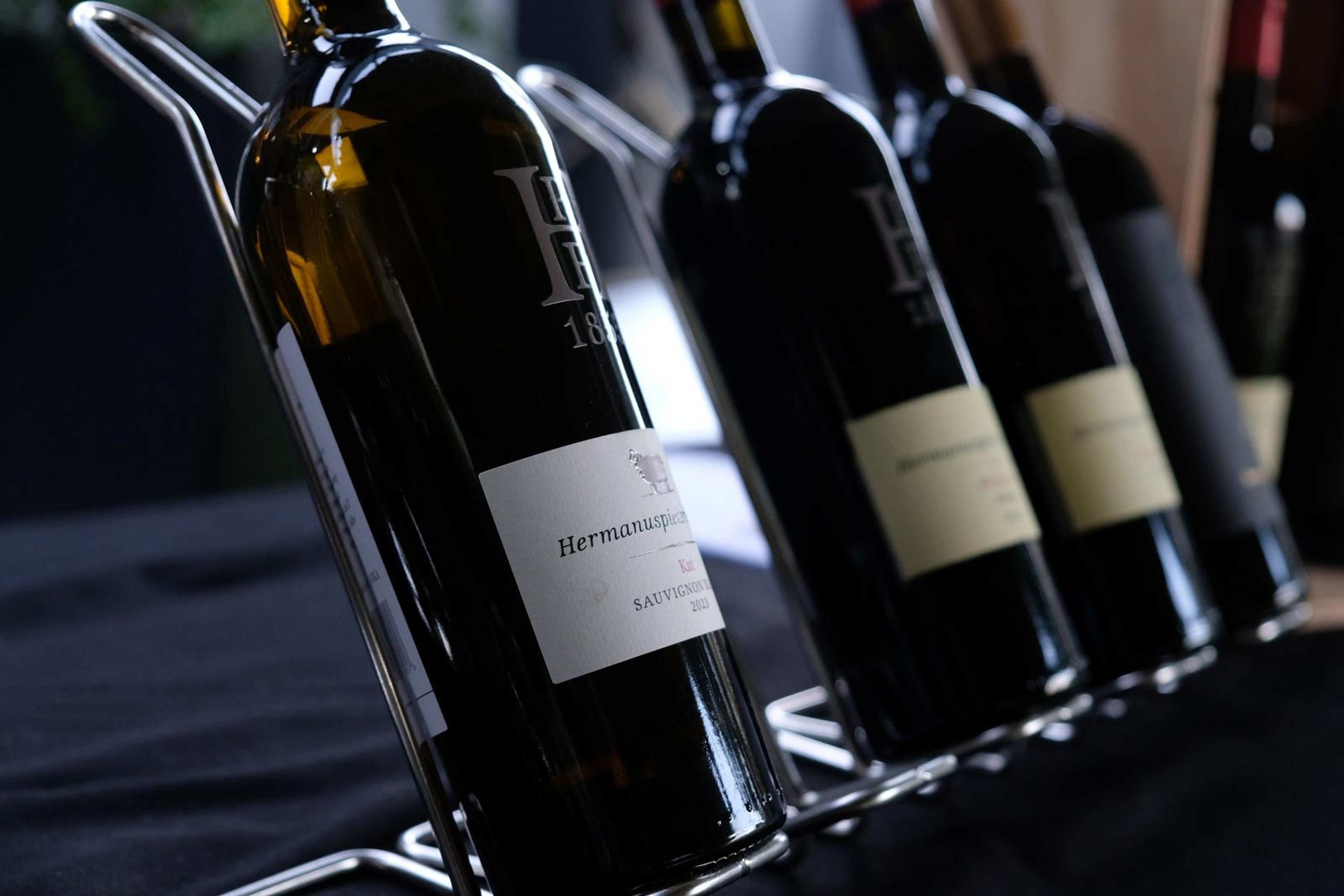 Bottles of Hermanuspietersfontein wine lined up on a rack at the opening tasting table