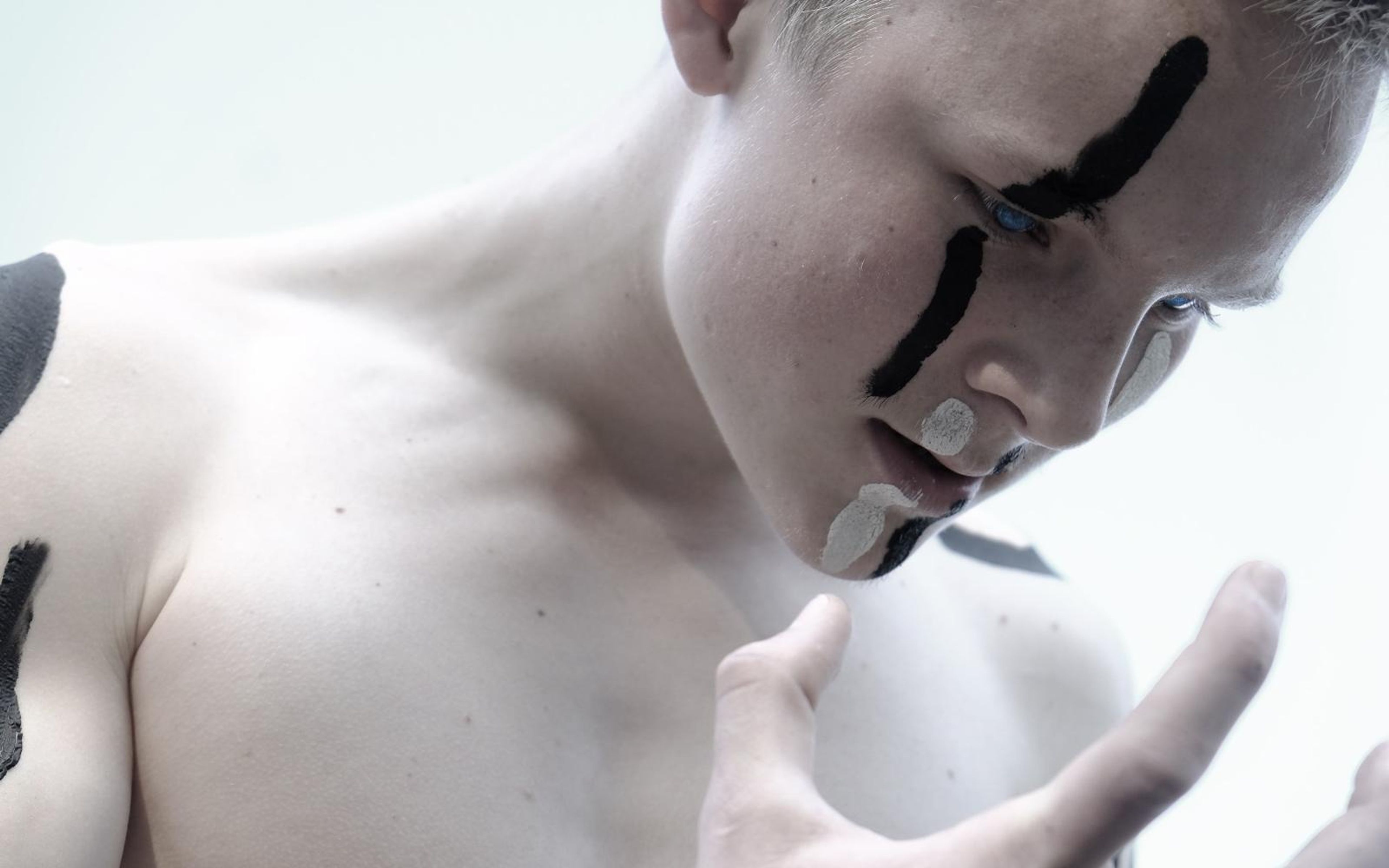 Colour version of the performer looking down with black face paint and a clawed hand in front of his chest