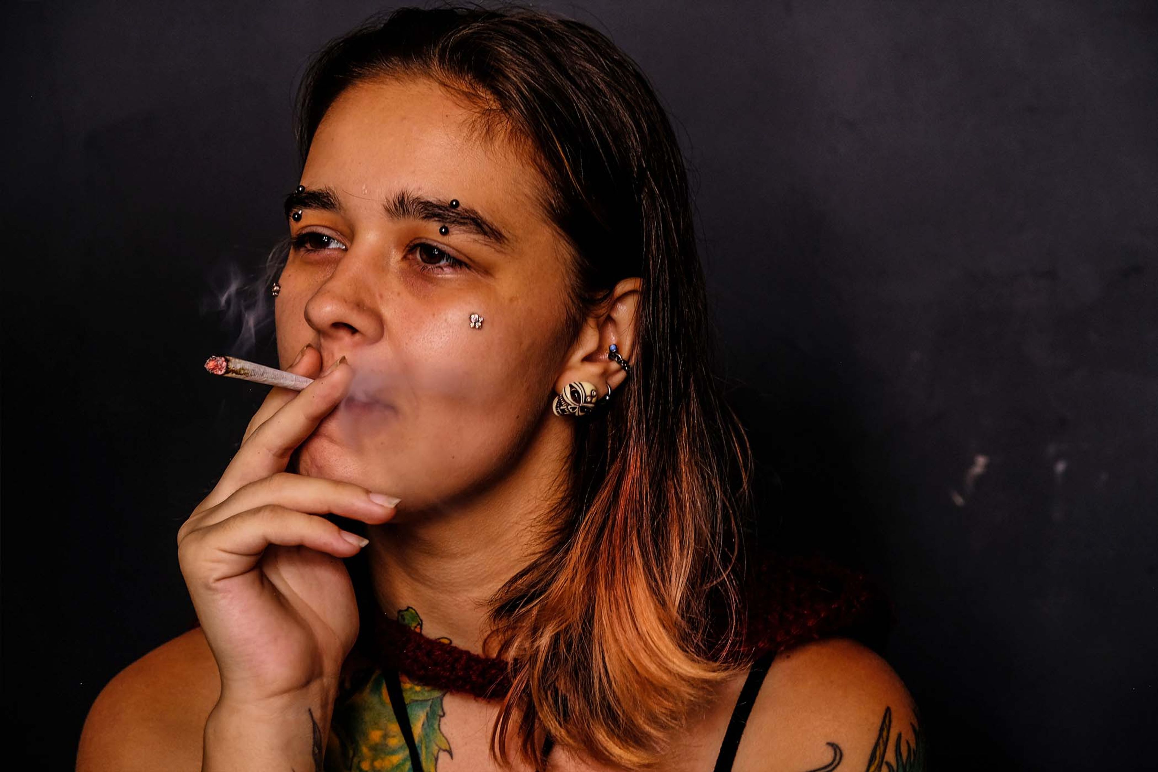 Side profile portrait, subject smoking a cigarette against a dark background, smoke rising