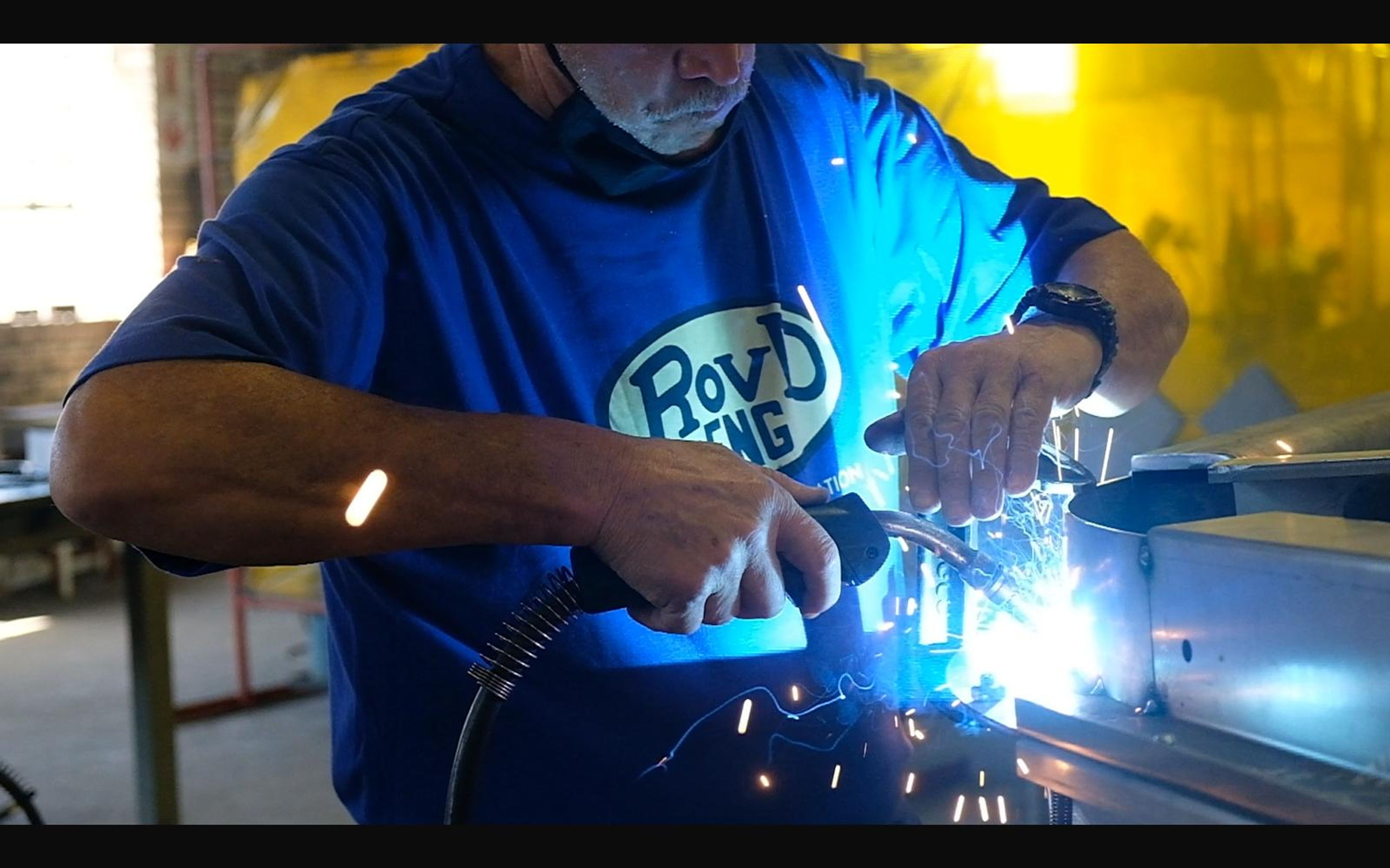 Worker in a ROVD shirt welding a small part