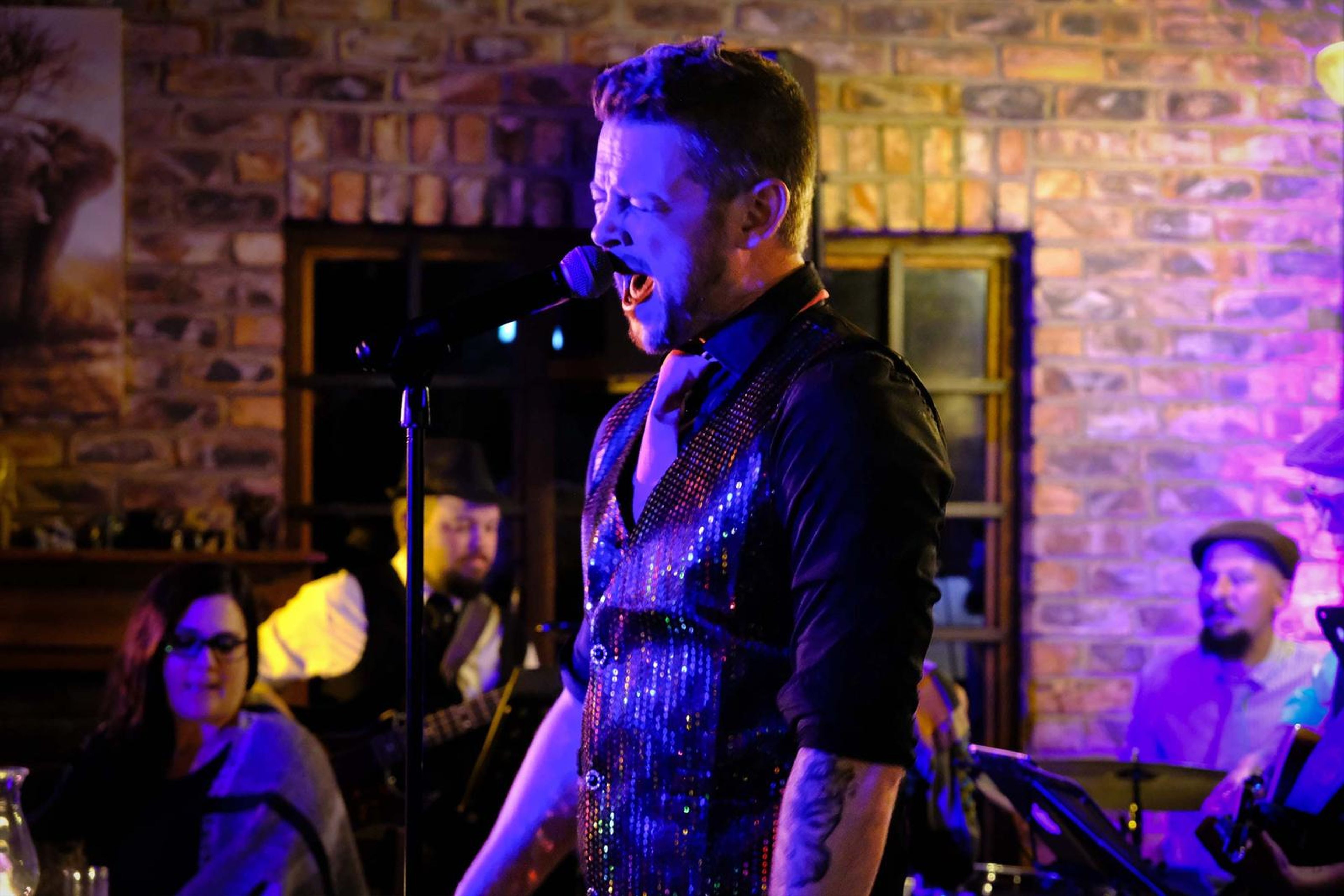 Lead singer singing with the band and diners behind him