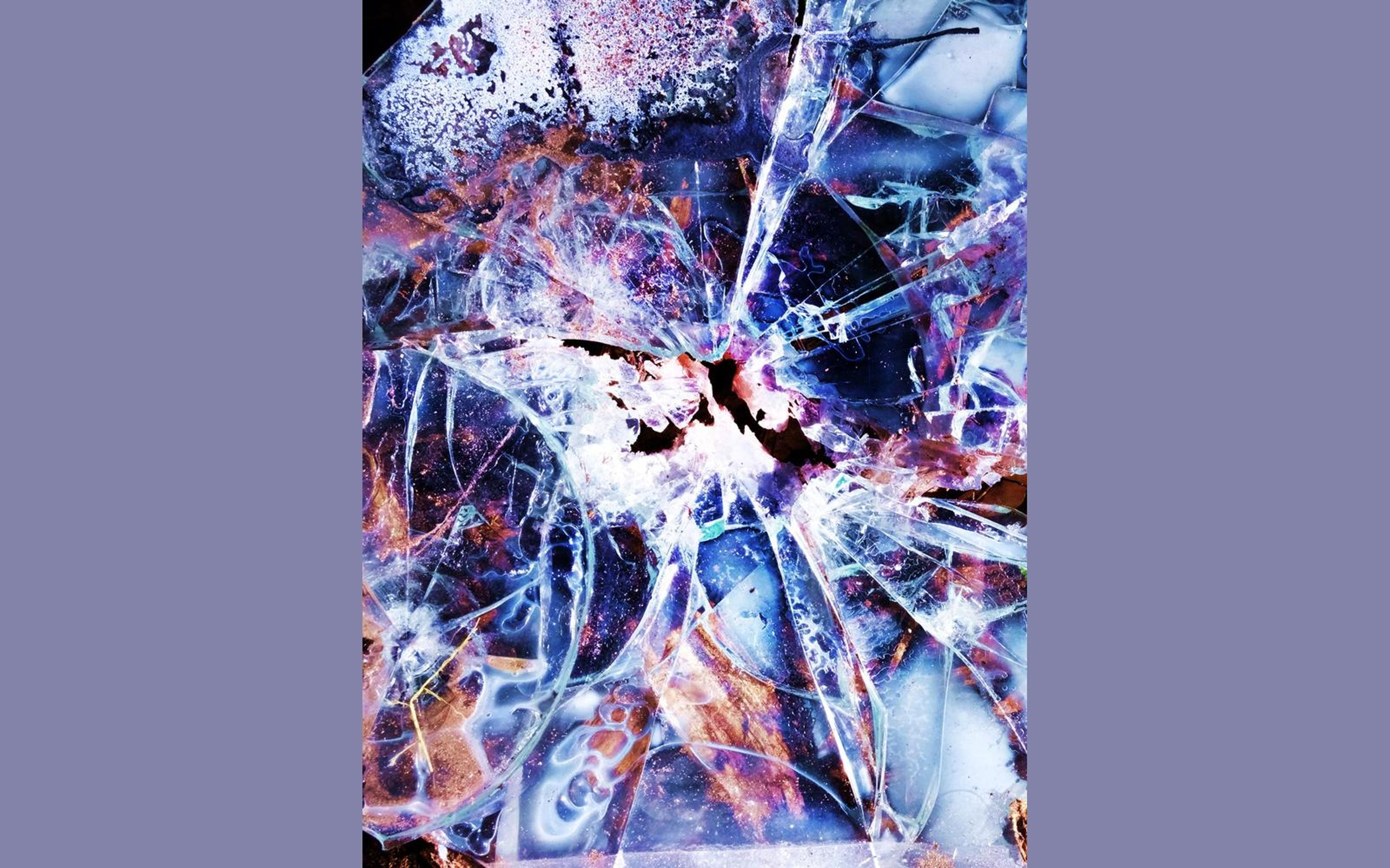 Macro view of shattered glass with blue, violet and orange colour overlays radiating from an impact point