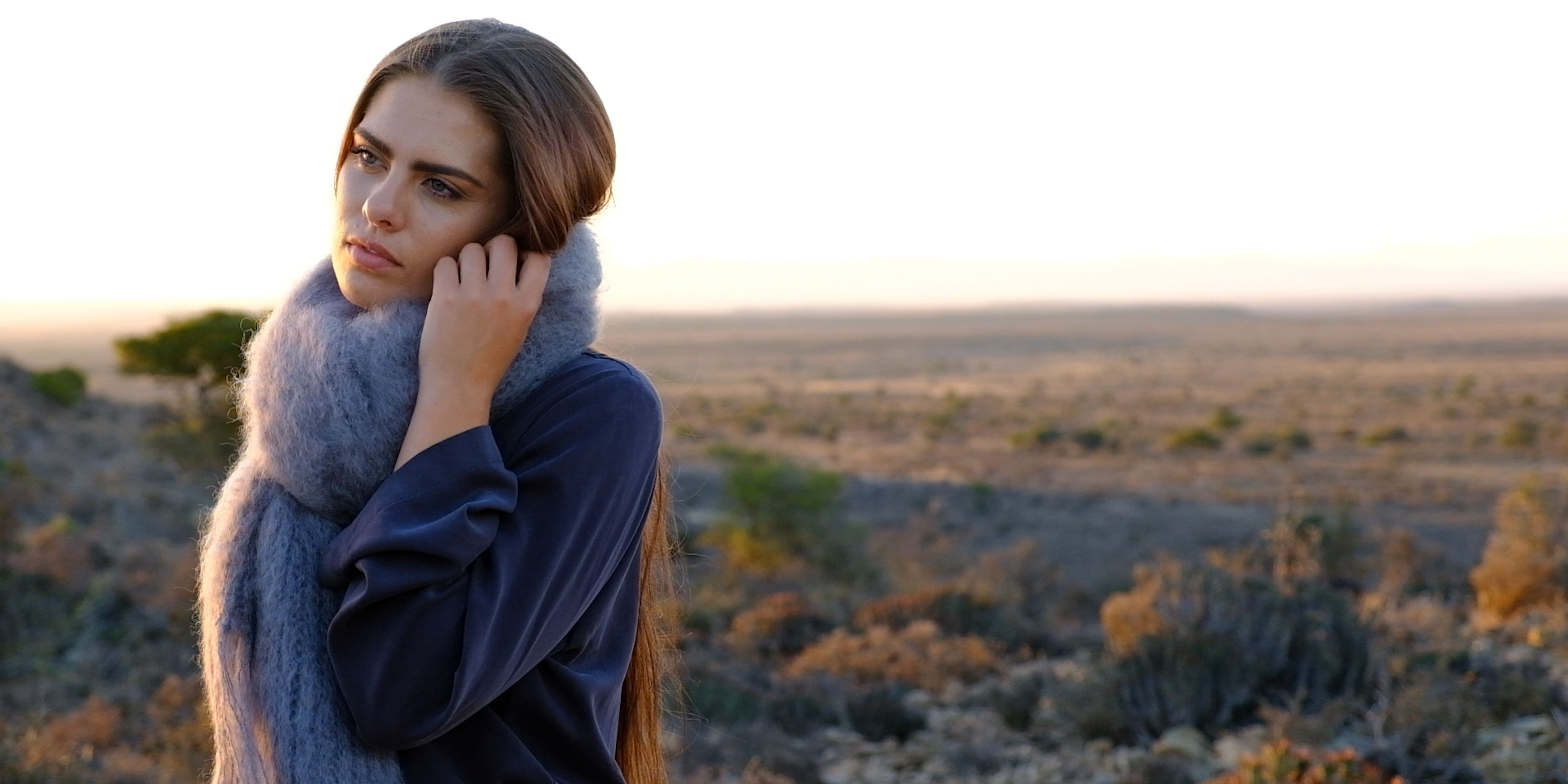 Model in a long orange-red mohair scarf in the last light