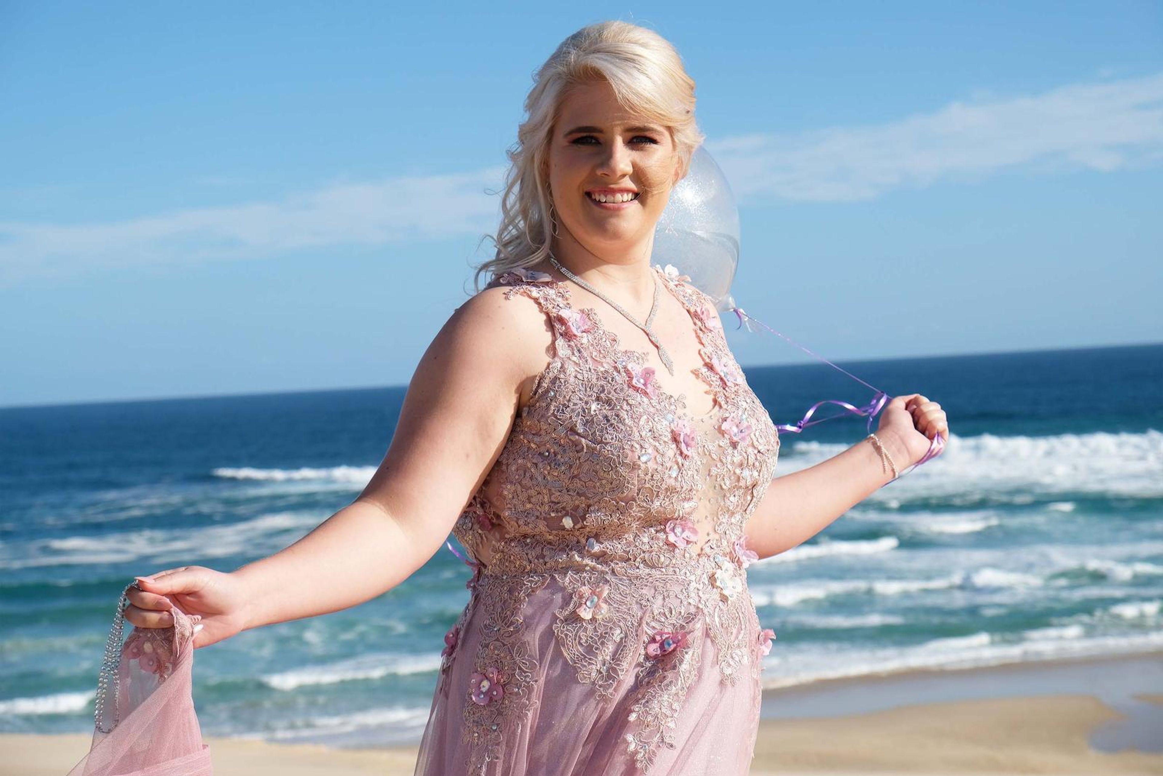 Lifting the skirt of the pink gown on the shoreline