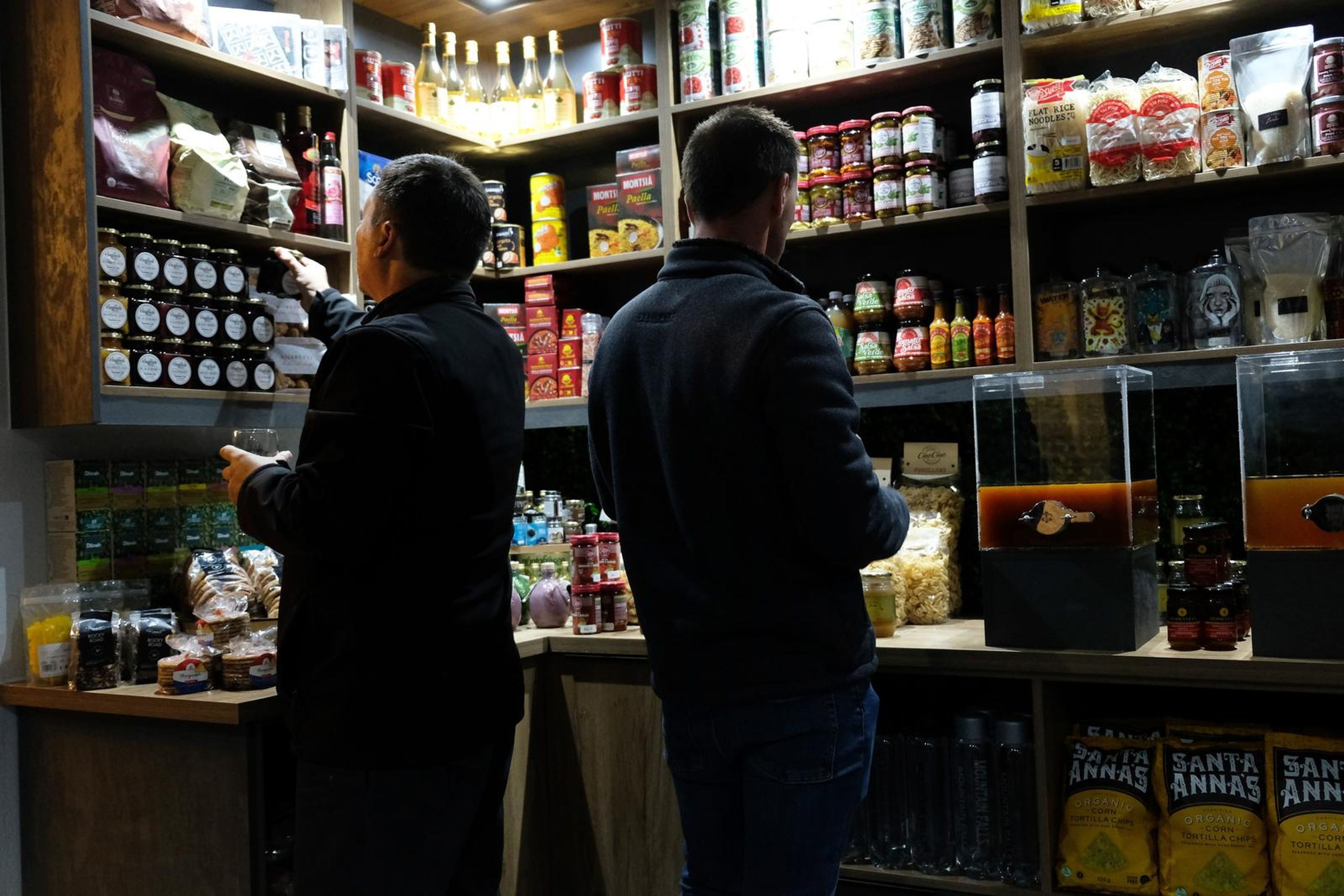 Two guests browsing the stocked pantry shelves