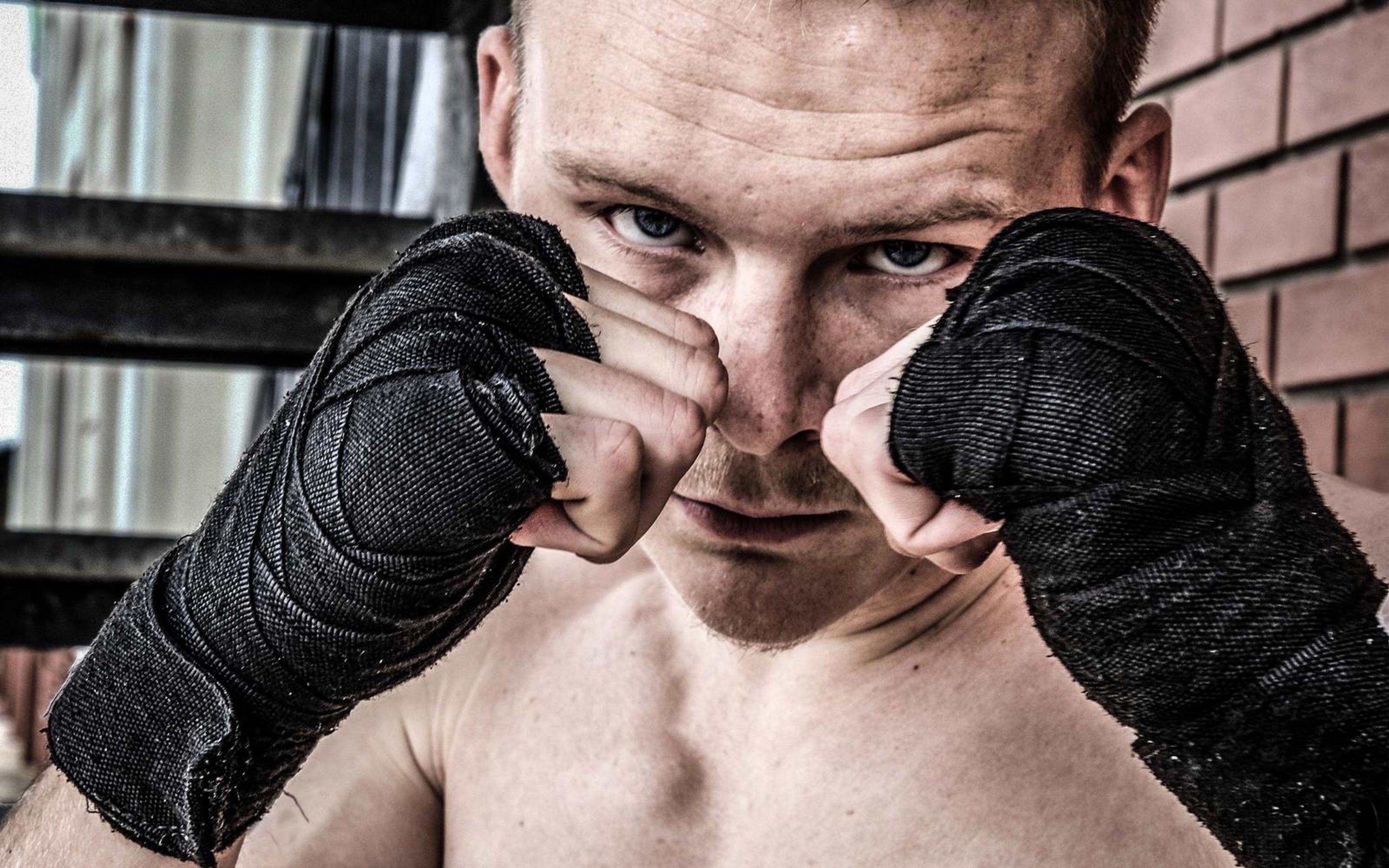 Fighter in a guard with both wrapped fists raised, in a darker graded frame
