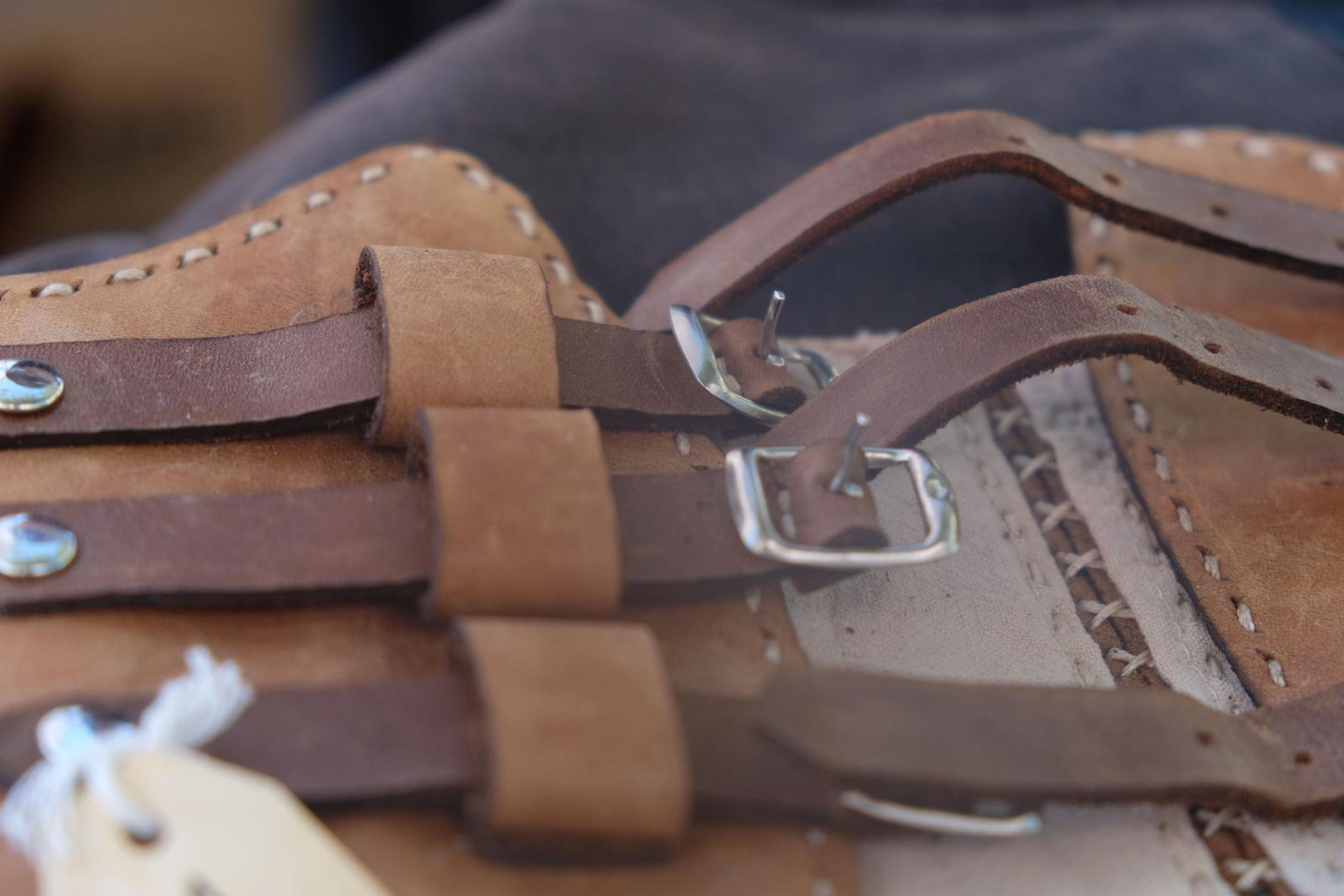 Close-up of tan and brown buckled leather straps with a handwritten tag