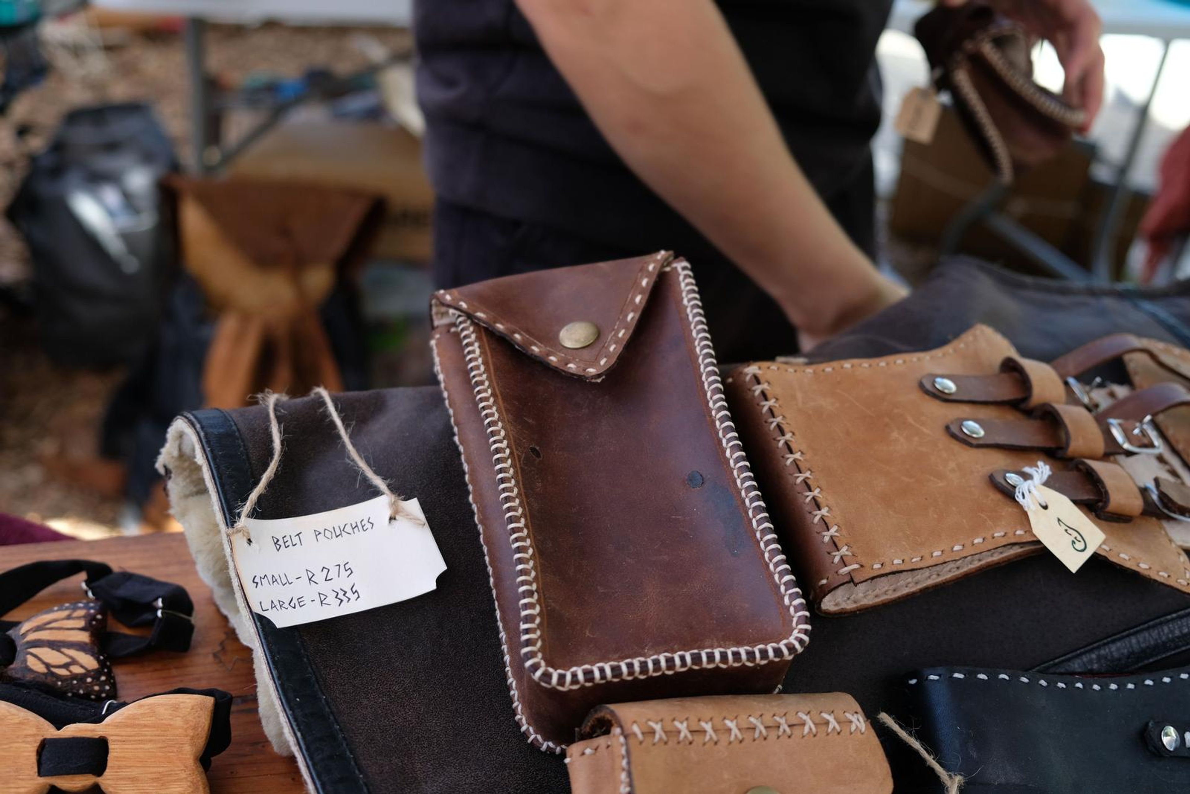 Hand holding a brown leather belt pouch with a price tag