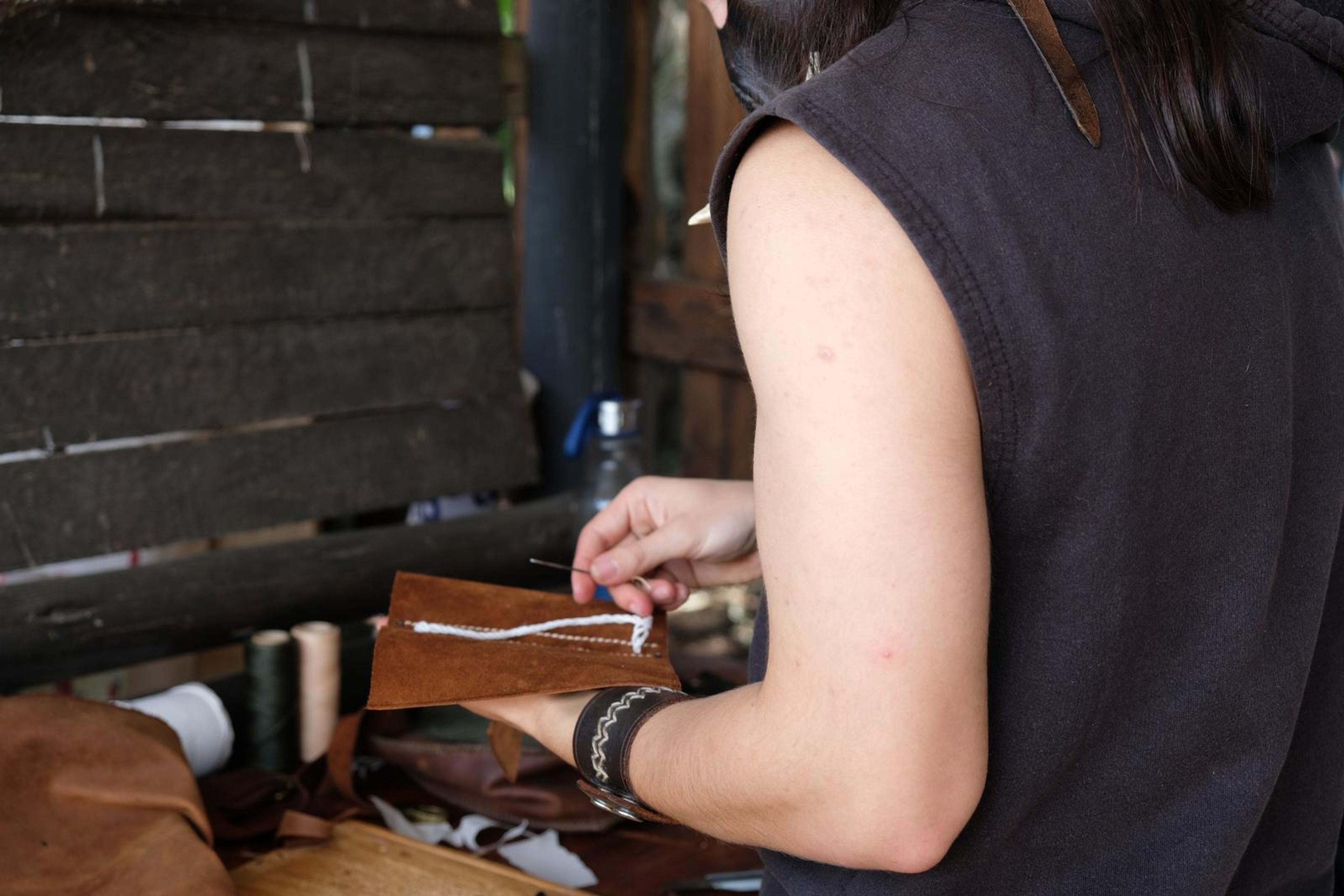Juuks leatherworker lacing a small leather piece by hand