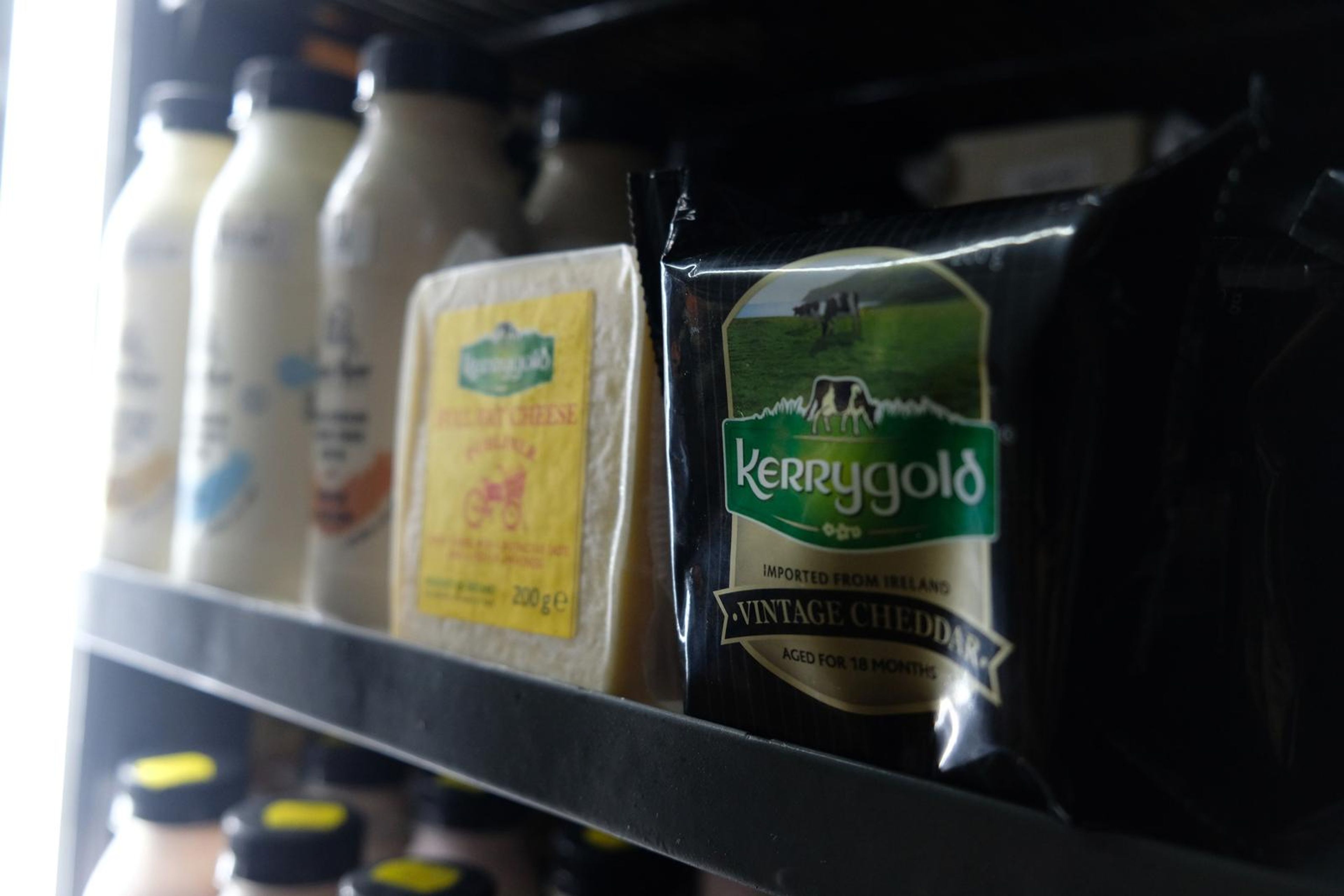 Bottles of fresh milk beside packs of Kerrygold cheese