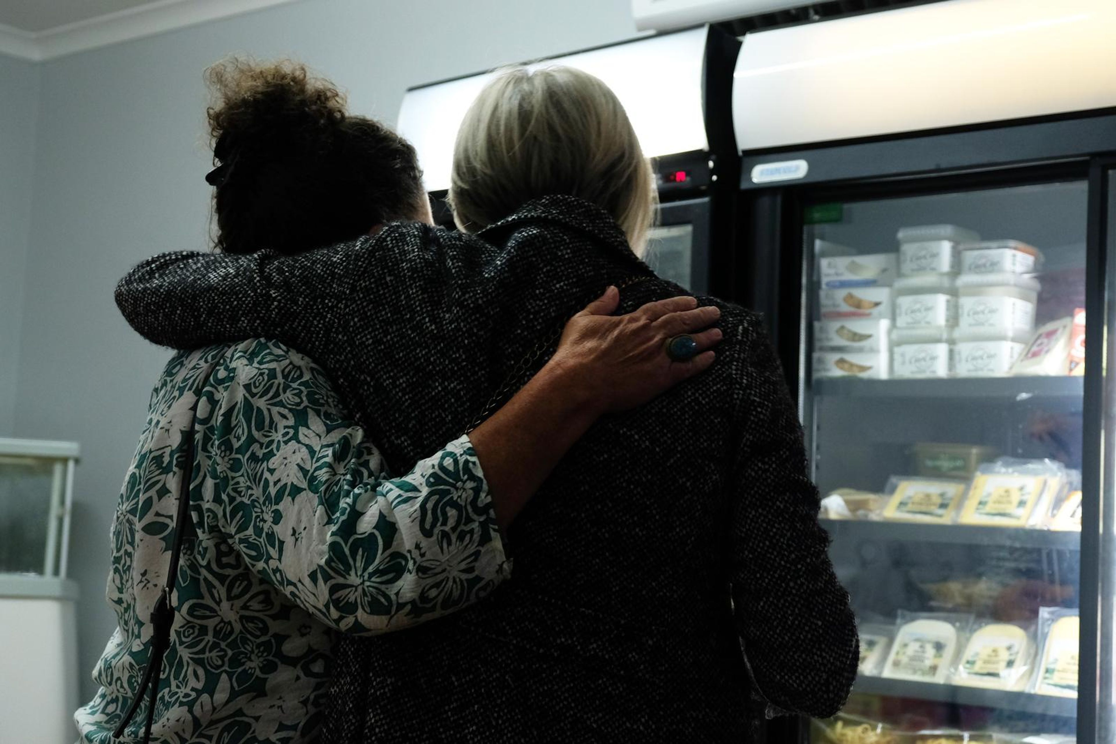 Two guests hugging in front of the fridge cabinets