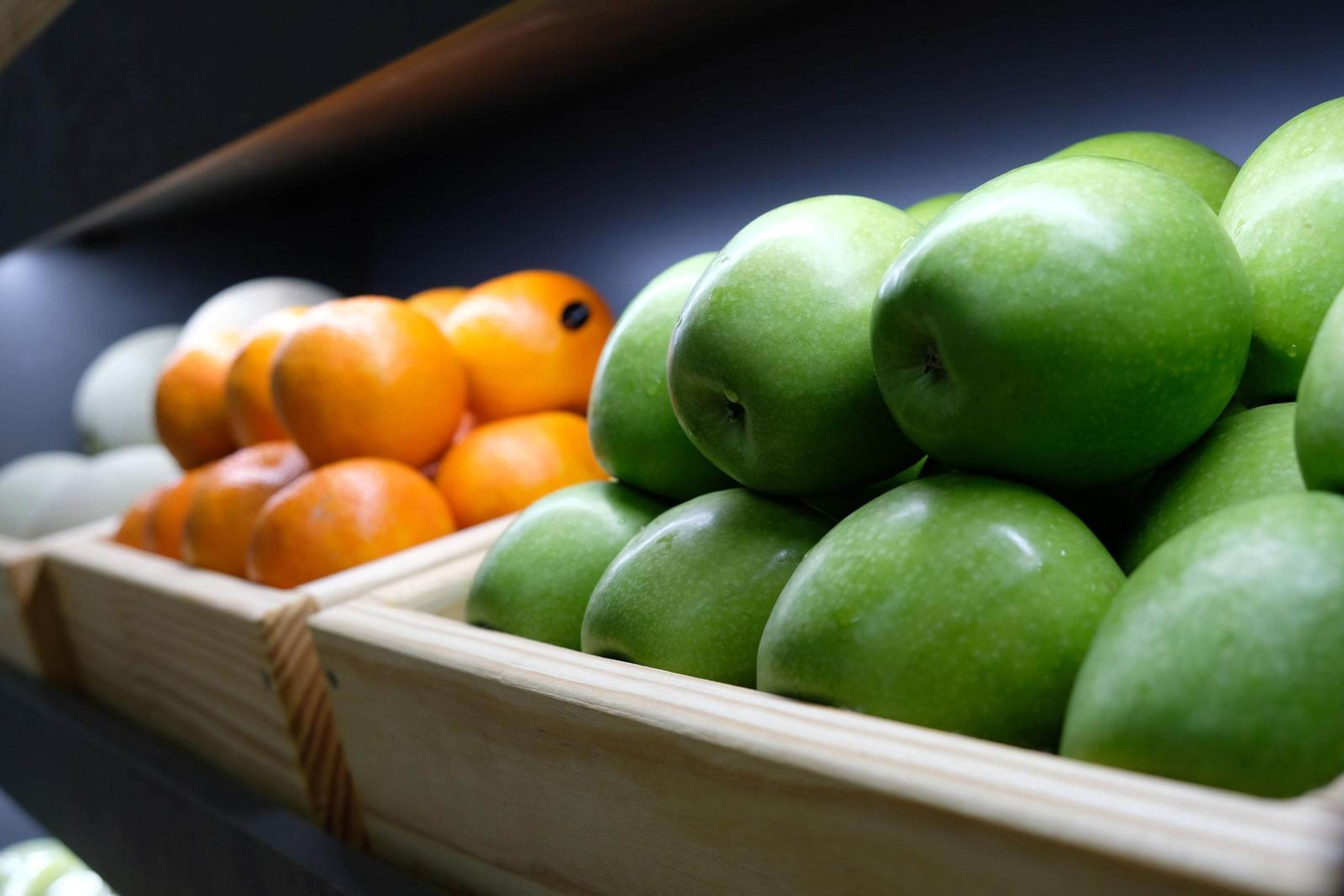 Oranges and green apples in wooden crates
