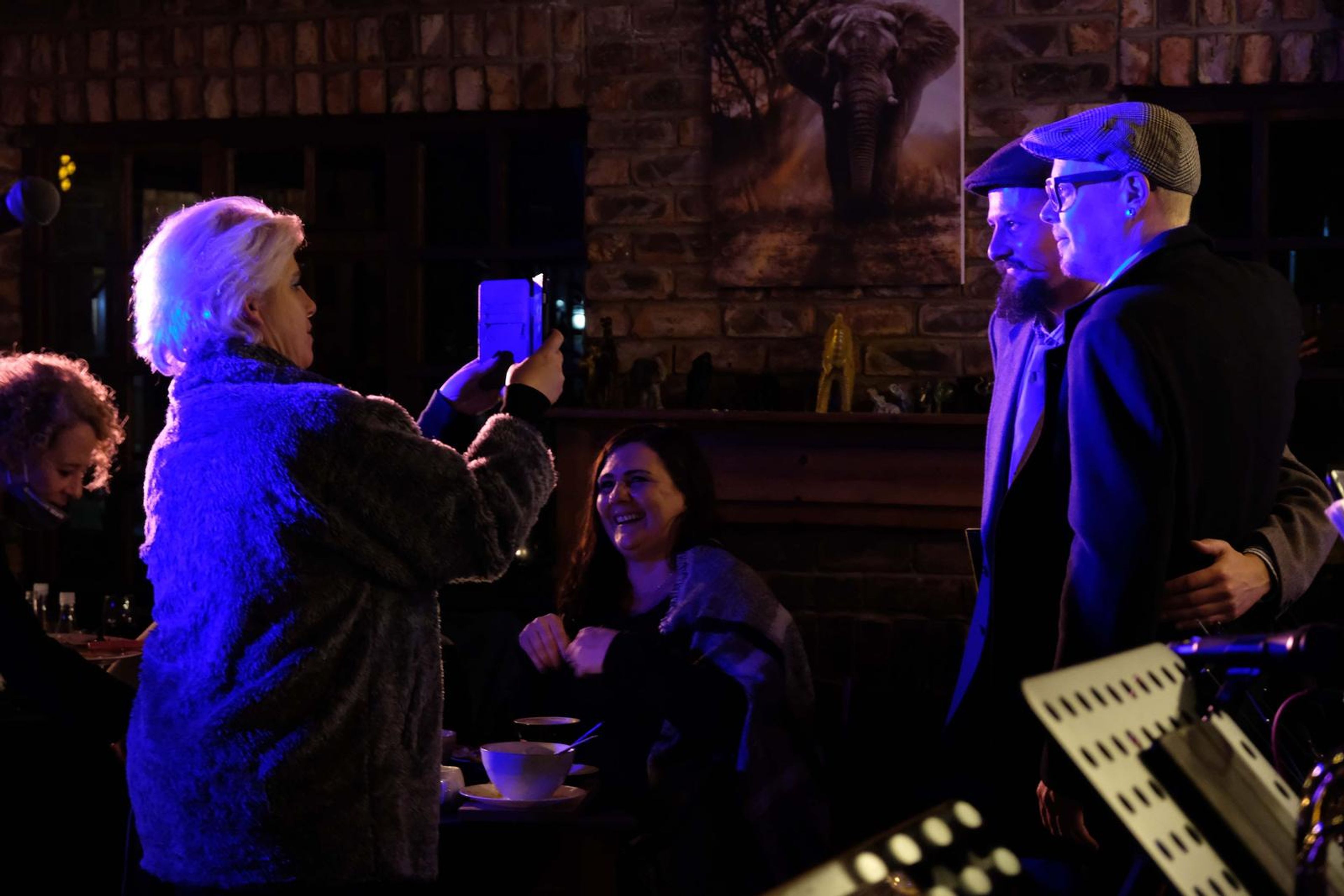 Guests filming the band on their phones while a singer sings beside them