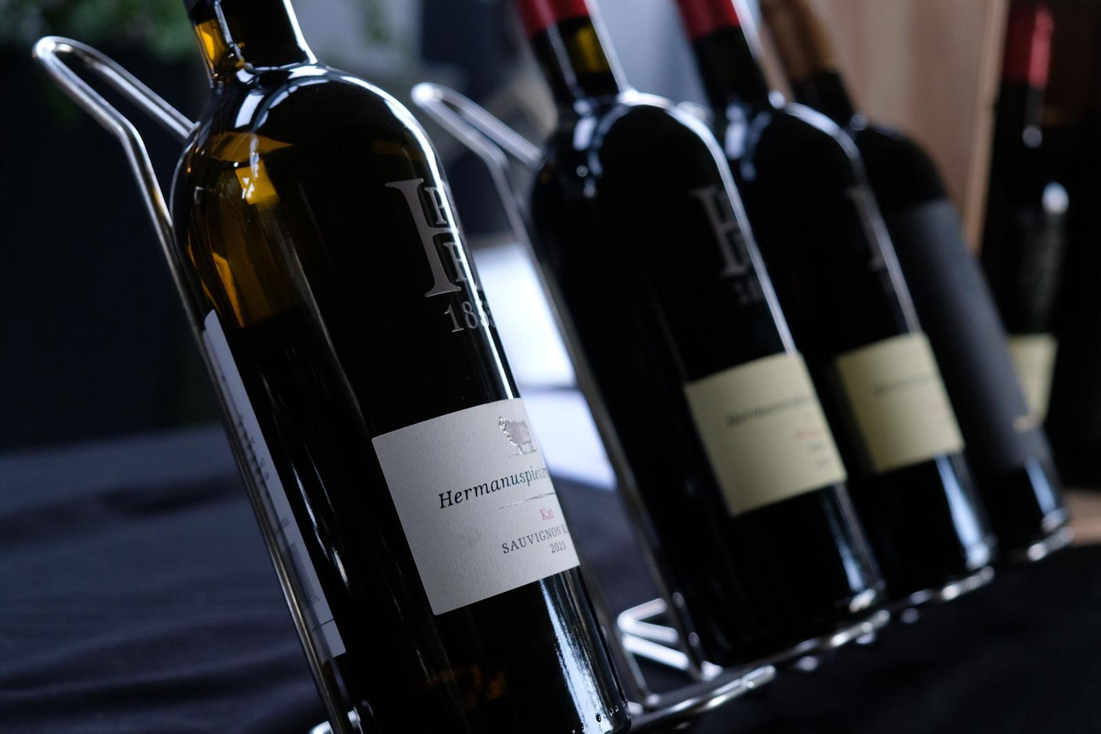 Bottles of Hermanuspietersfontein wine leaning on a rack with the labels showing