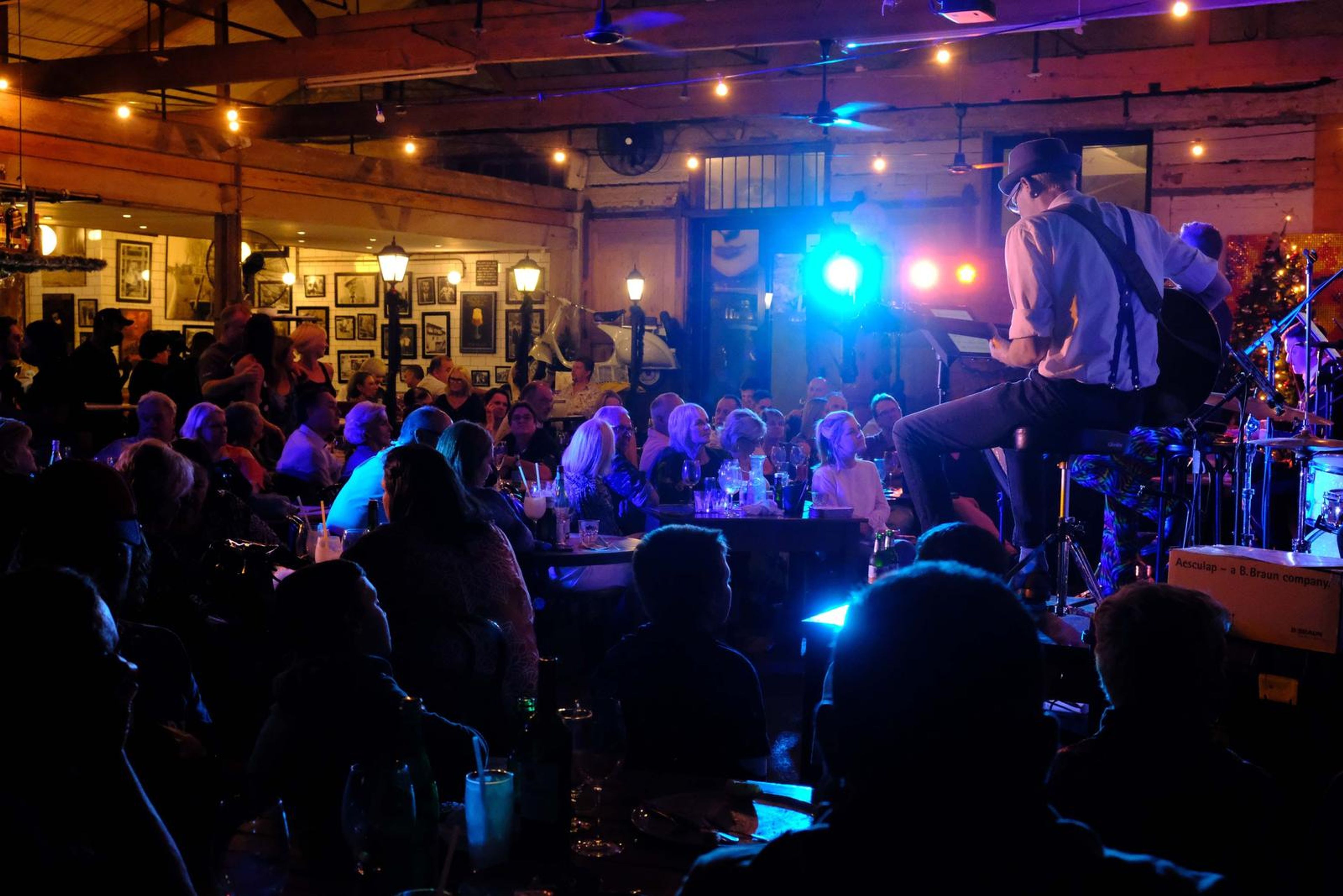 Wide view of the band lit in blue across the packed restaurant