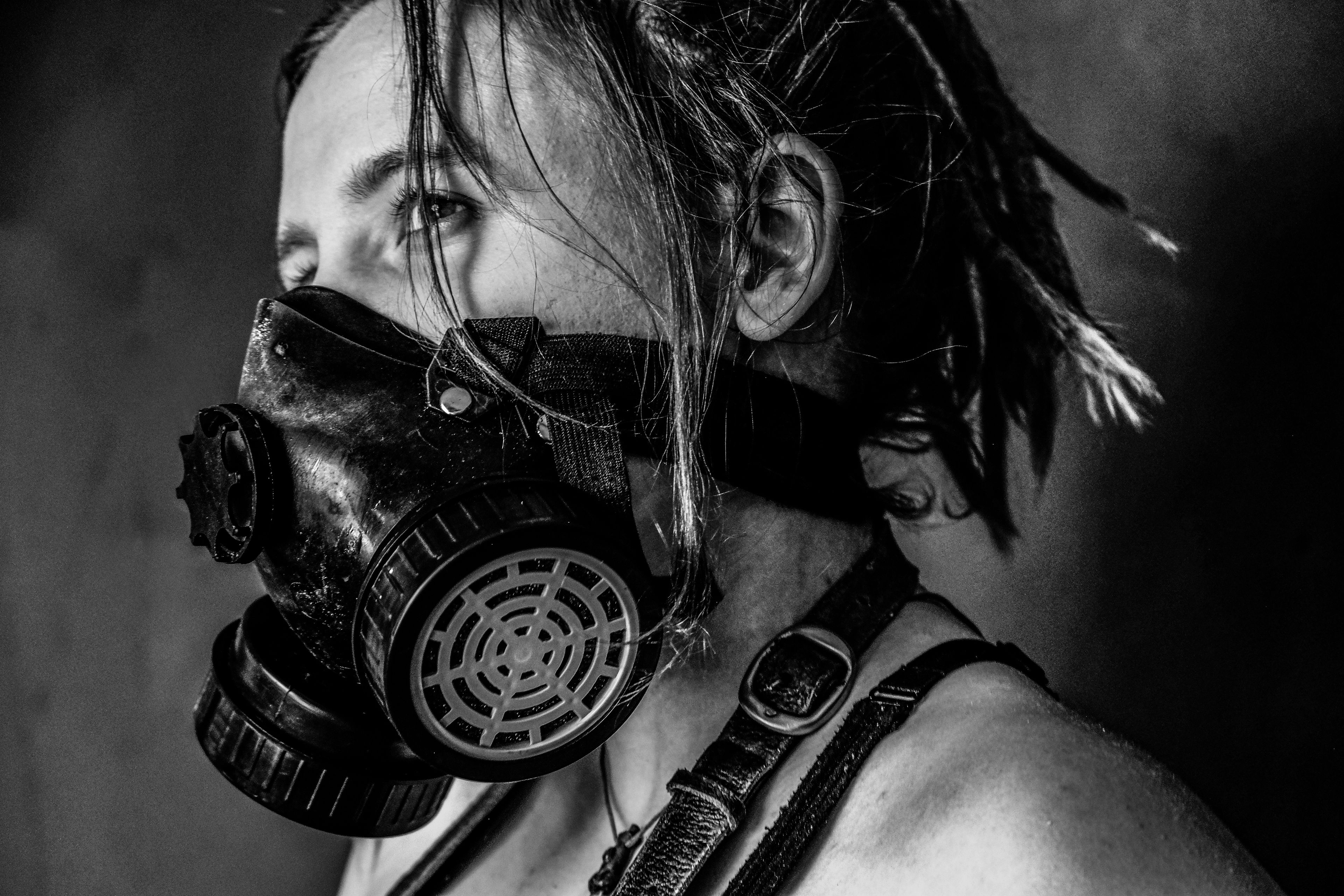 Black and white side profile portrait, subject wearing a gas mask and leather harness strap