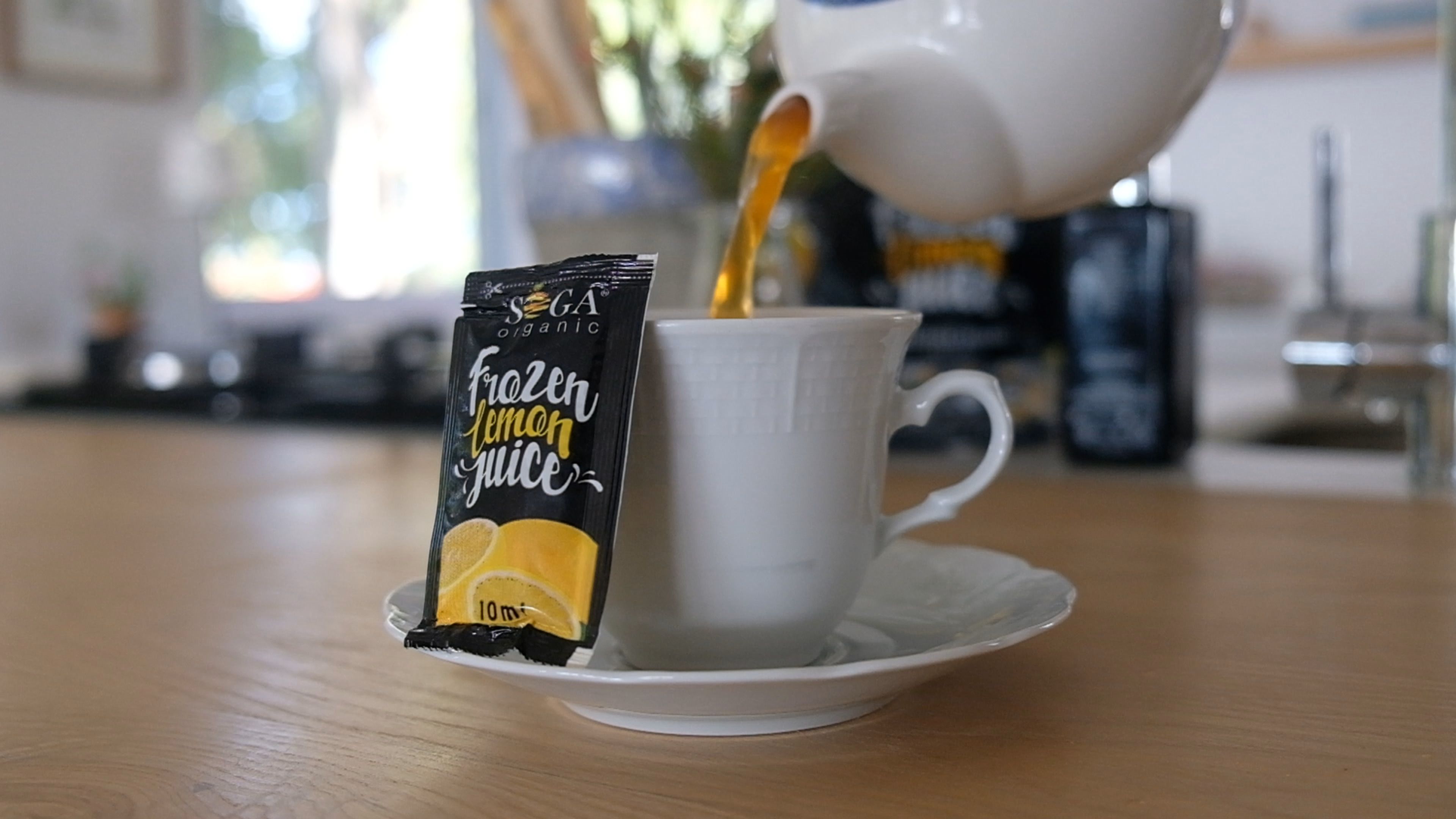 Tea being poured into a cup beside a standing SOGA lemon juice sachet