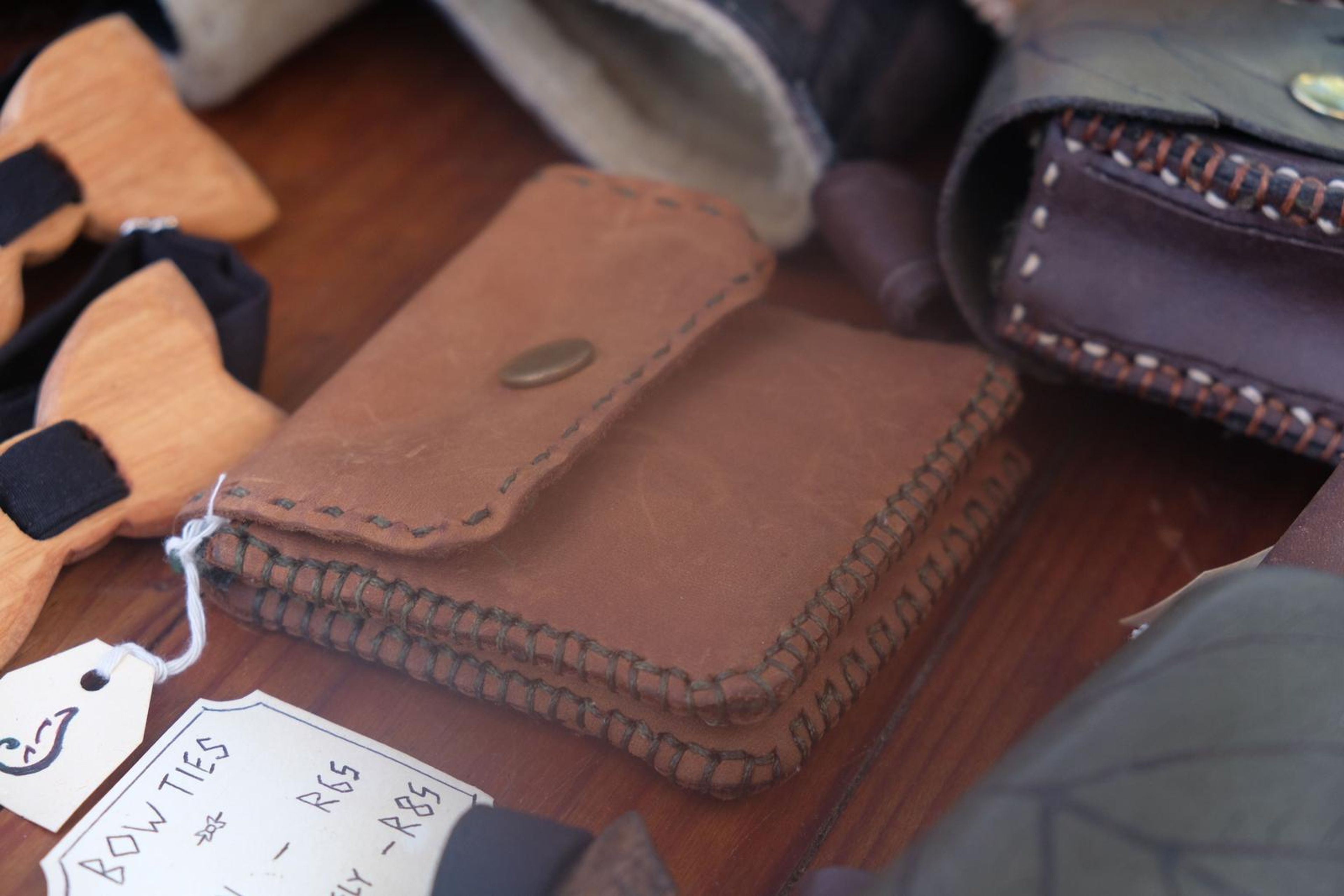 Carved wooden bow ties and tan leather pouches on the table