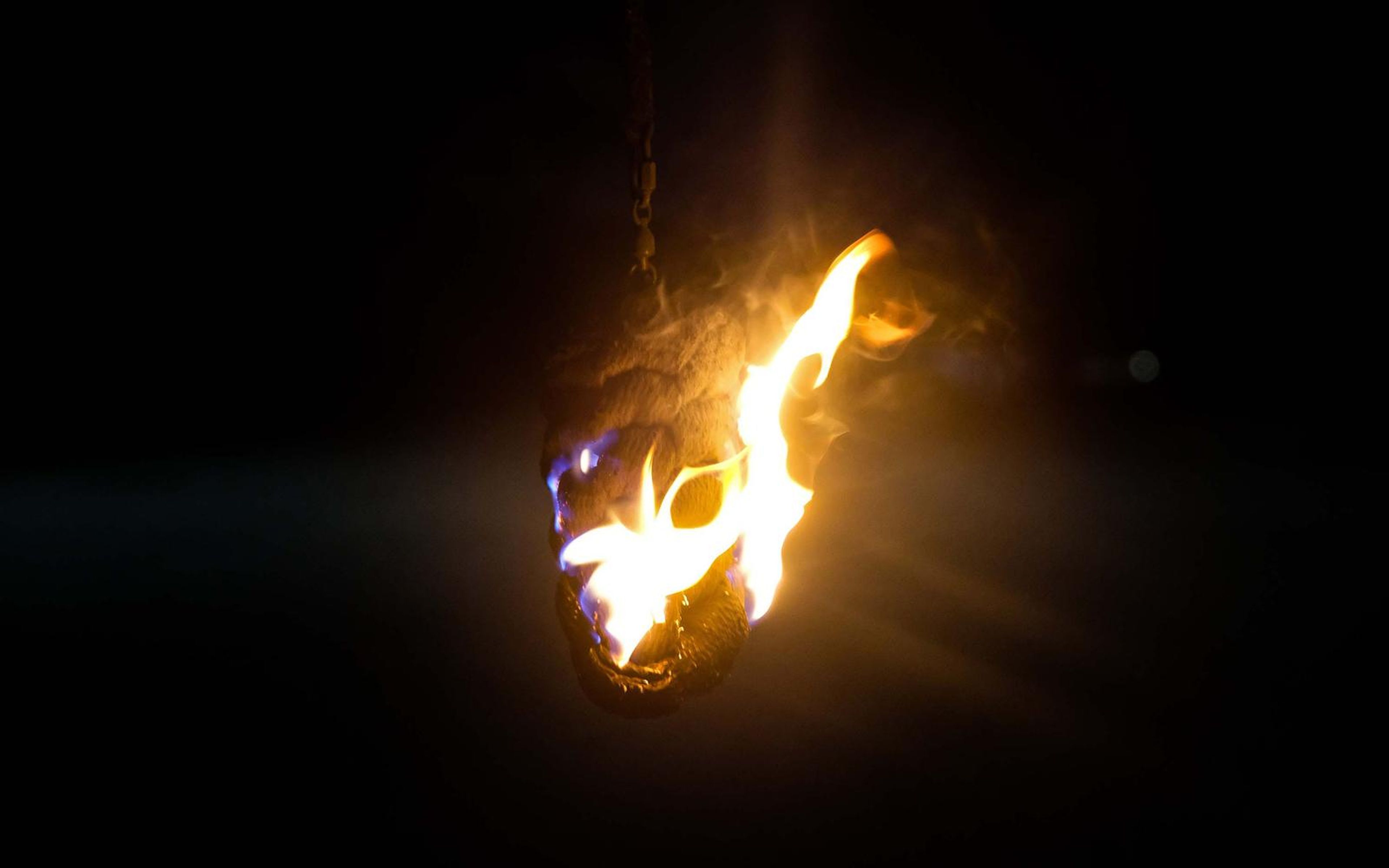 Flame burning on a hanging prop in darkness, bent toward the right