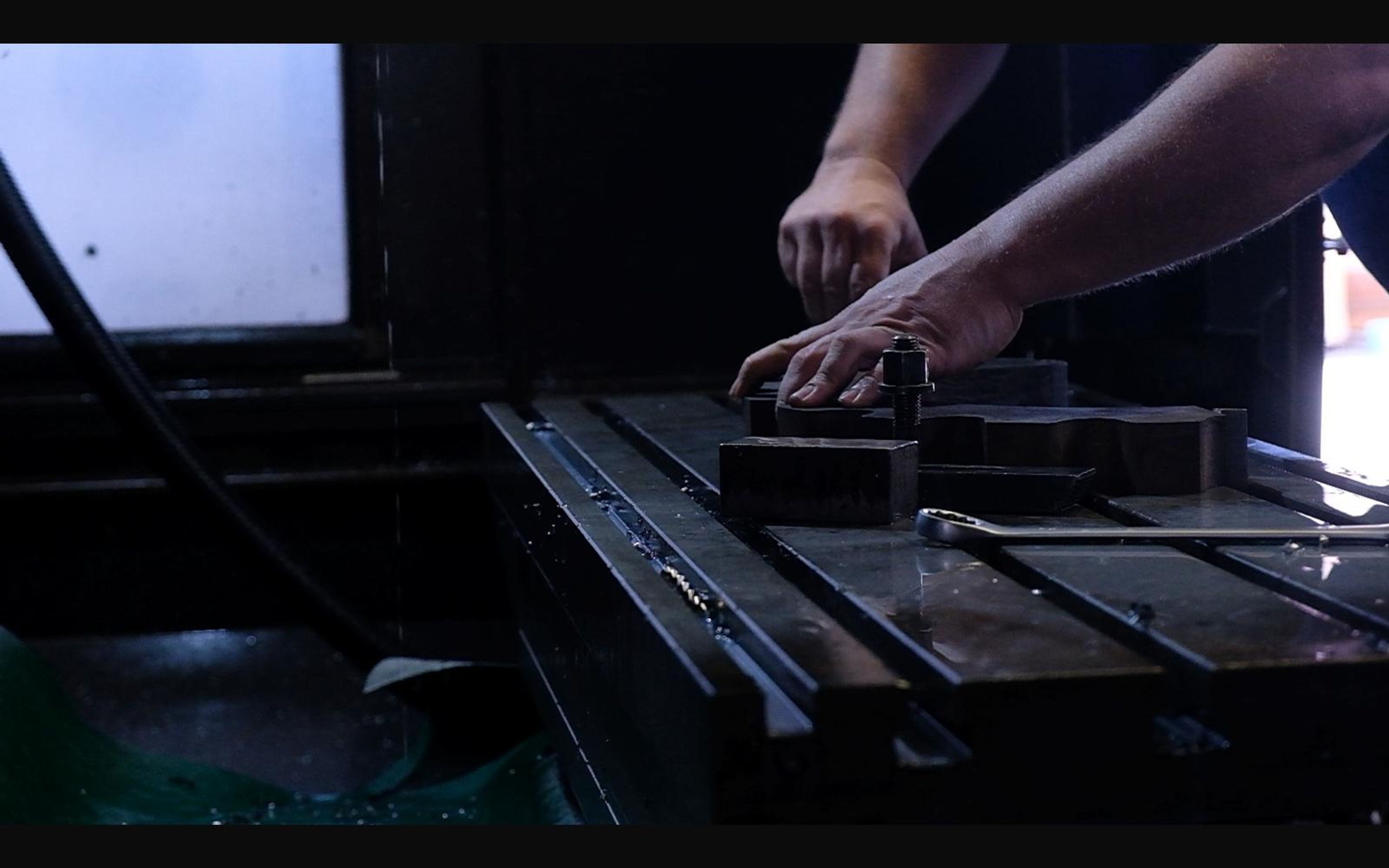Hands loading a part onto a milling machine bed