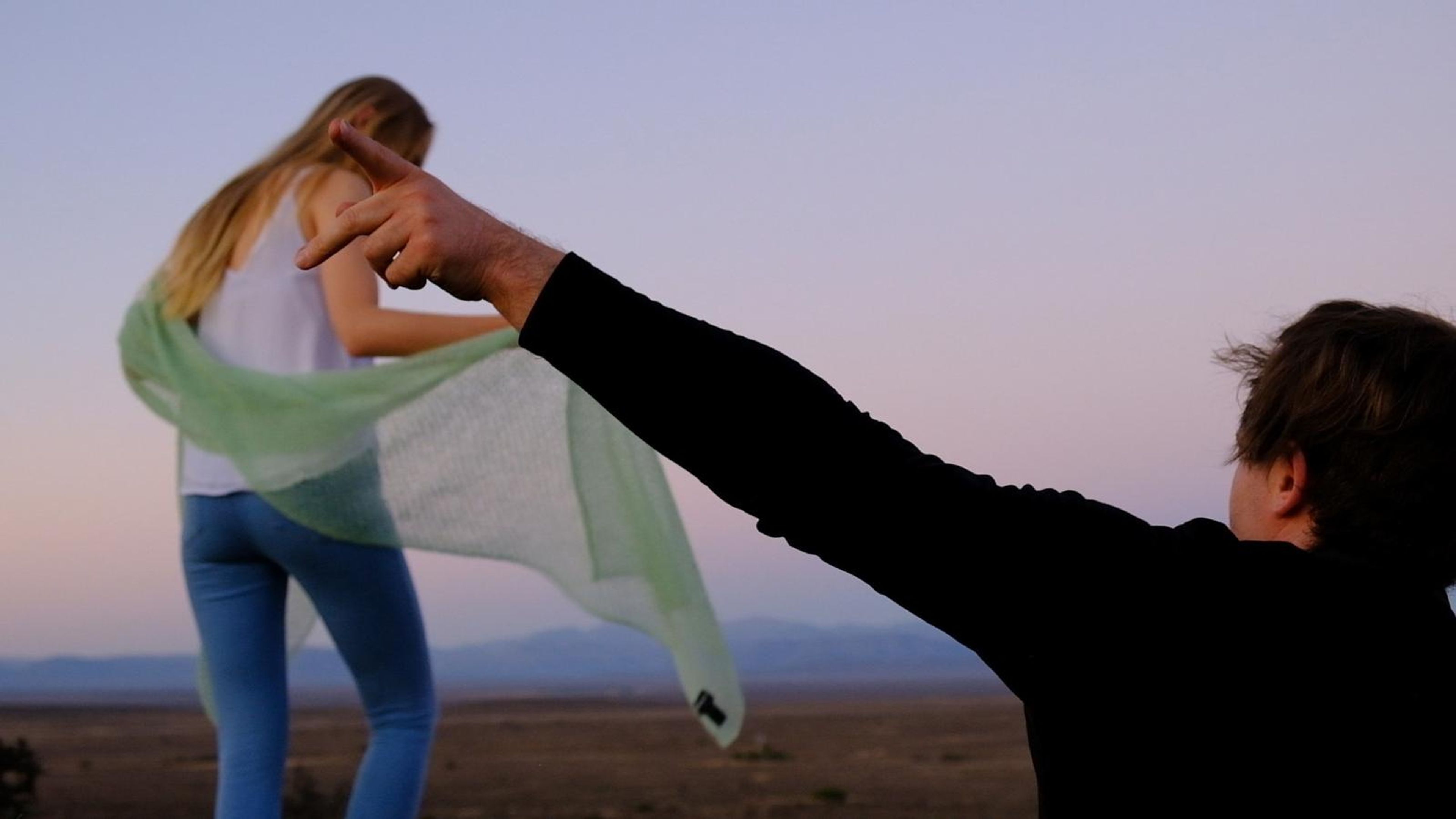 Stylist holding up a pale green scarf as the wind catches it