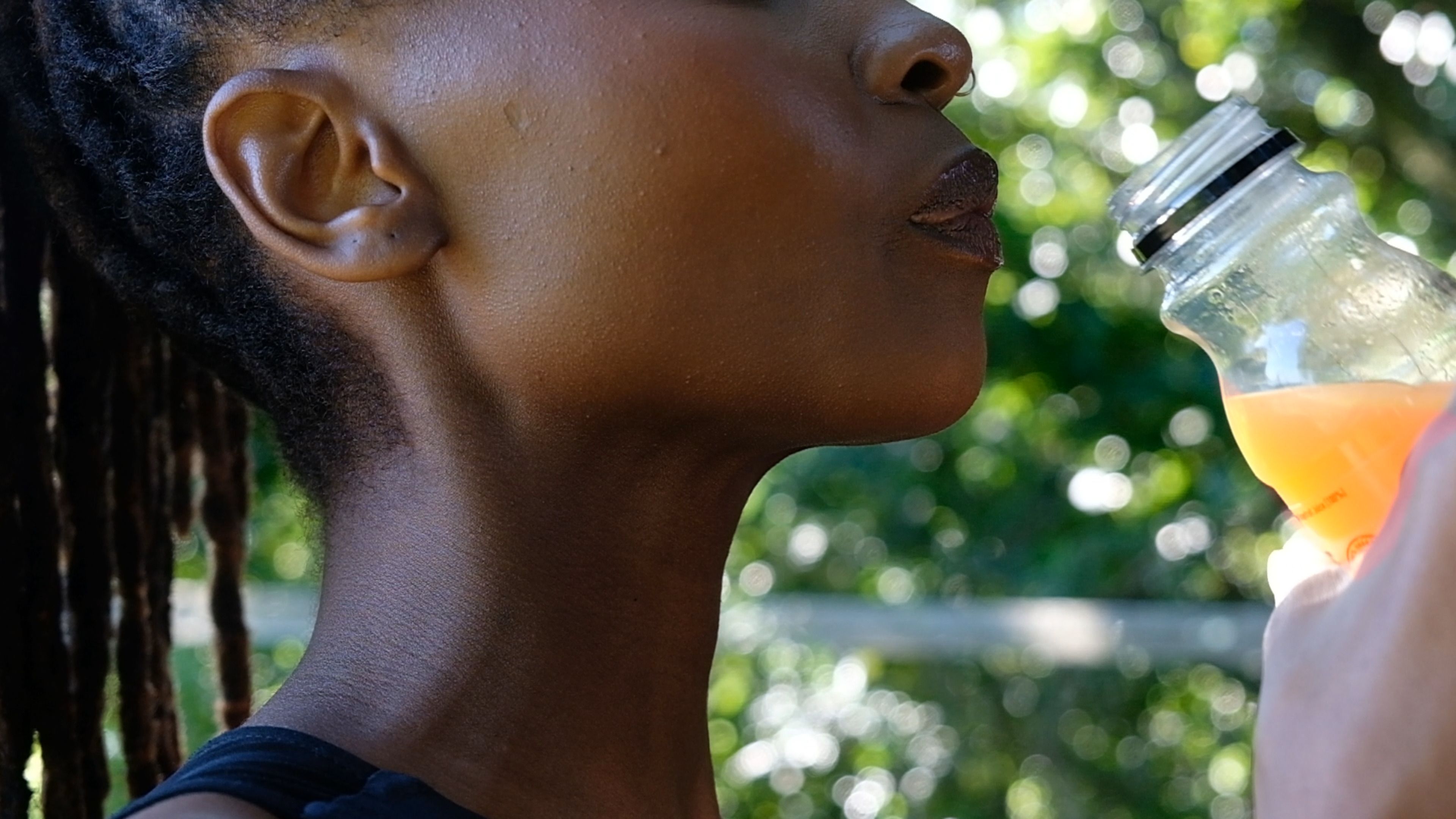 Side view of a woman tilting a bottle of juice to drink