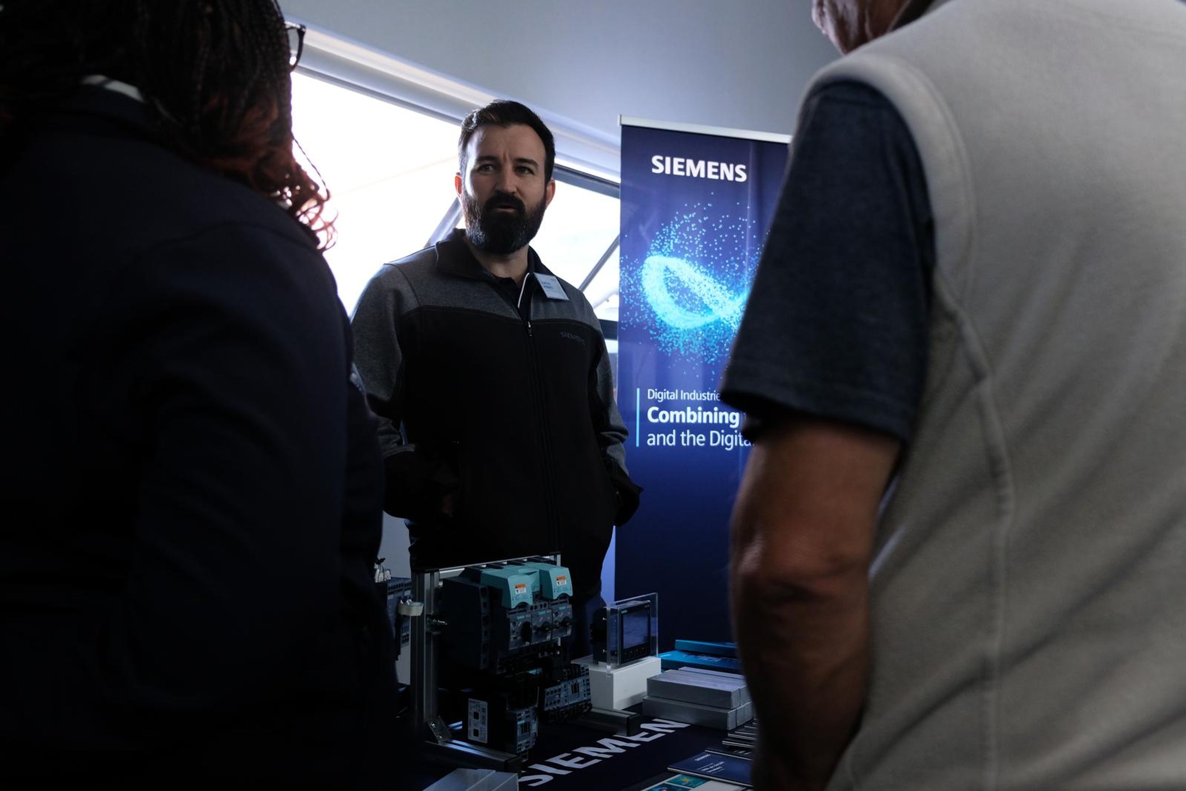 Siemens presenter at the stand beside a digital industries banner