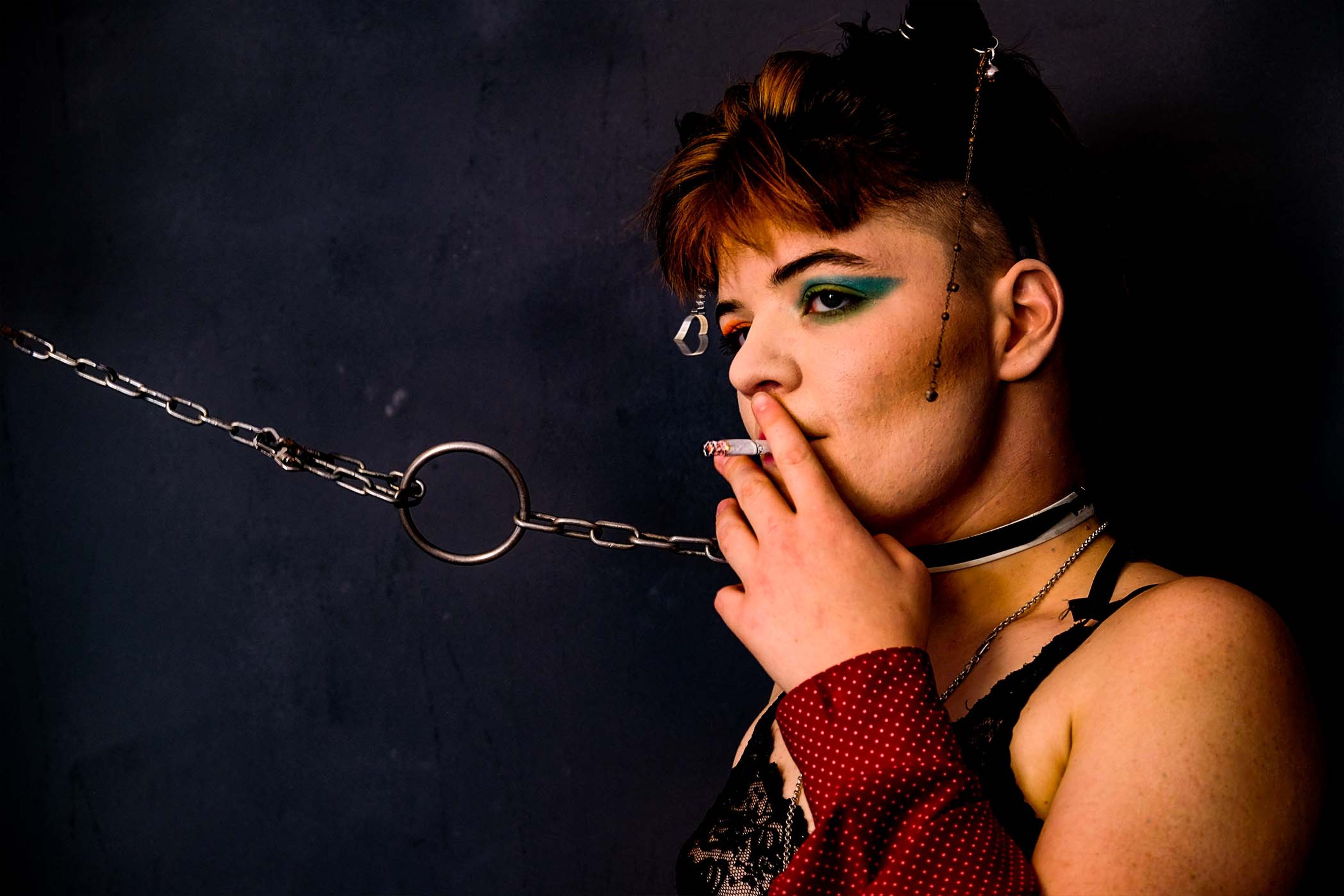 Side profile portrait, subject smoking a cigarette, chain looped through a ring choker