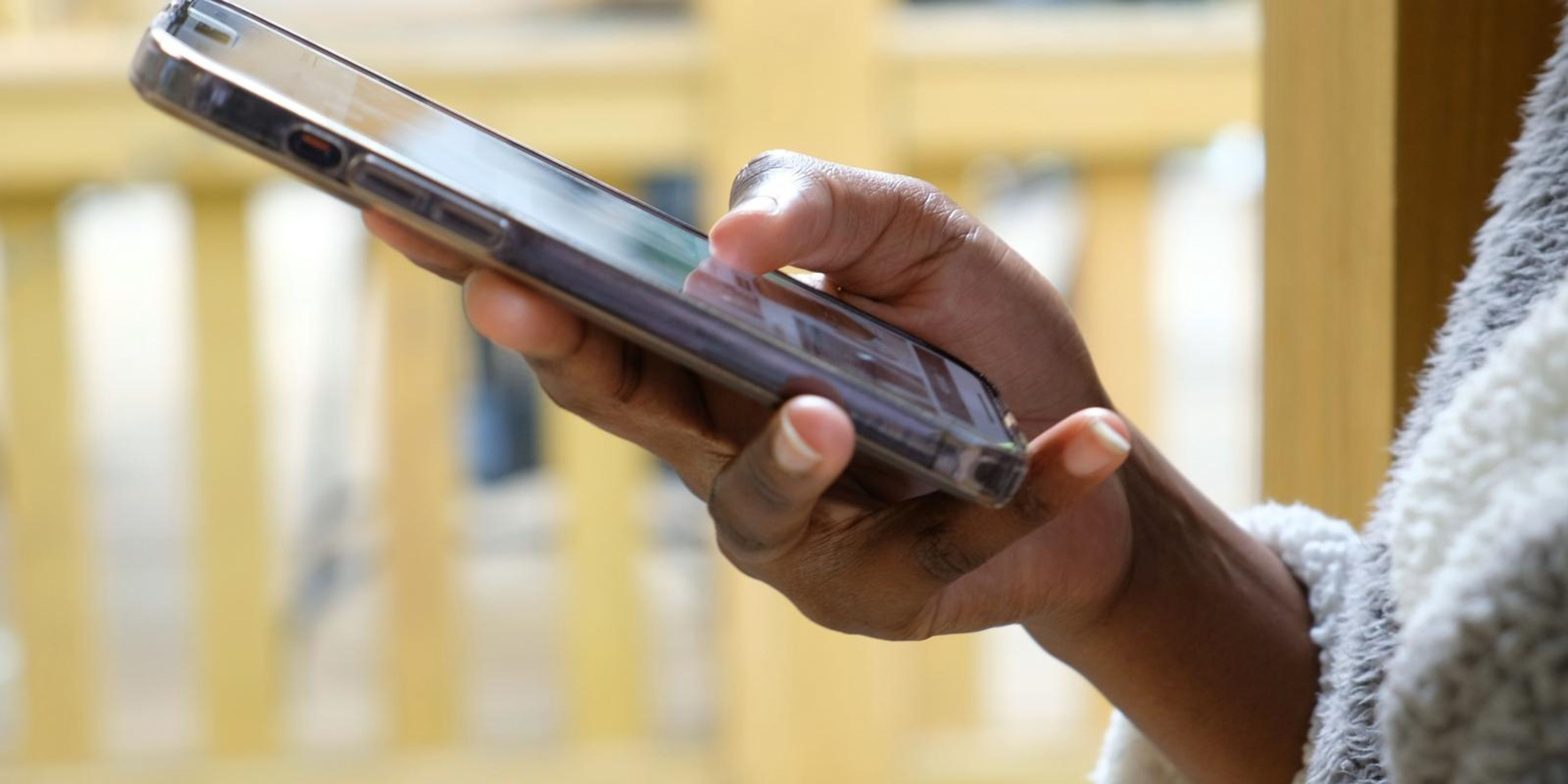 Frame of a hand scrolling a phone on a wooden porch
