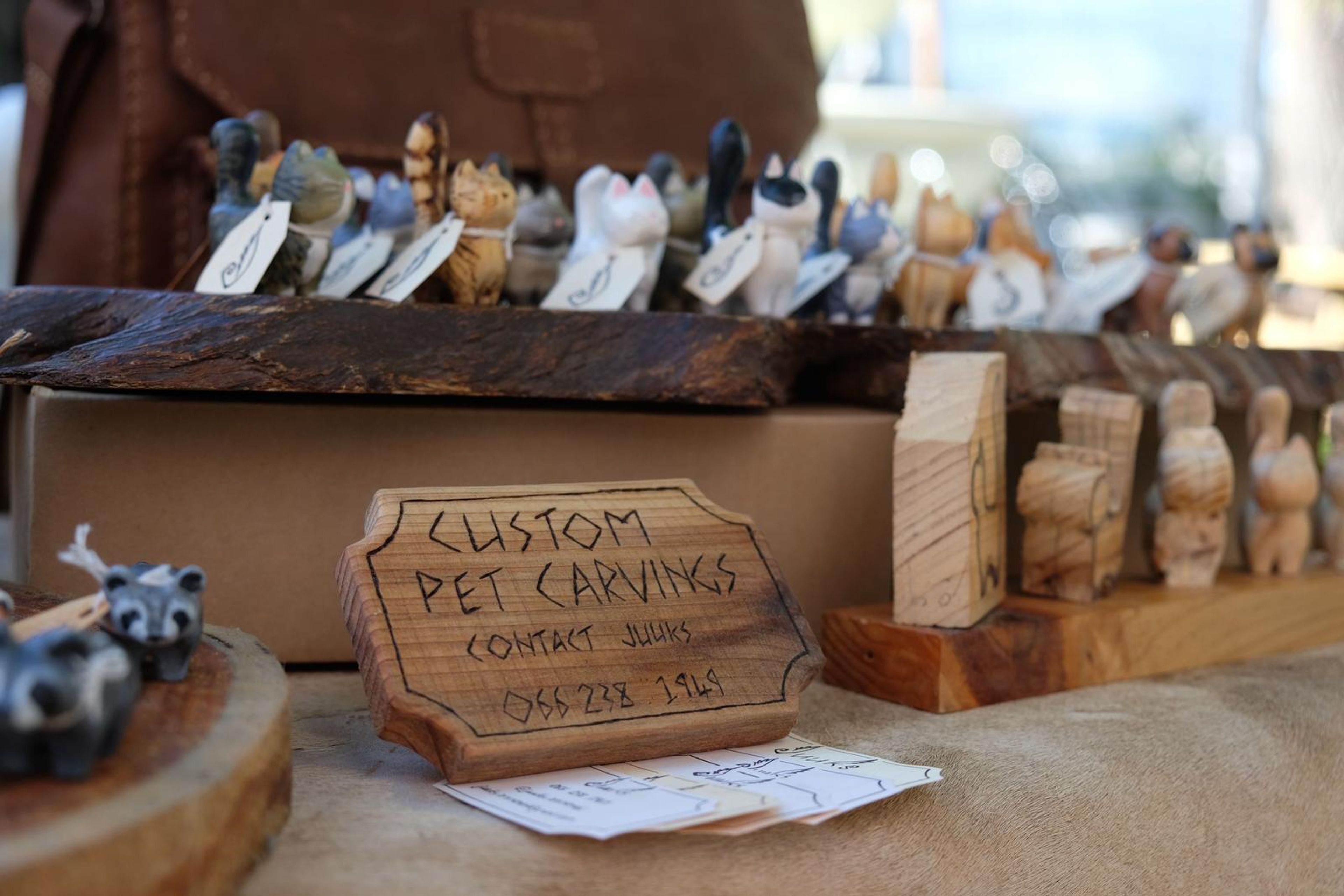 Custom Pet Carvings sign with carved wooden pets on the stall