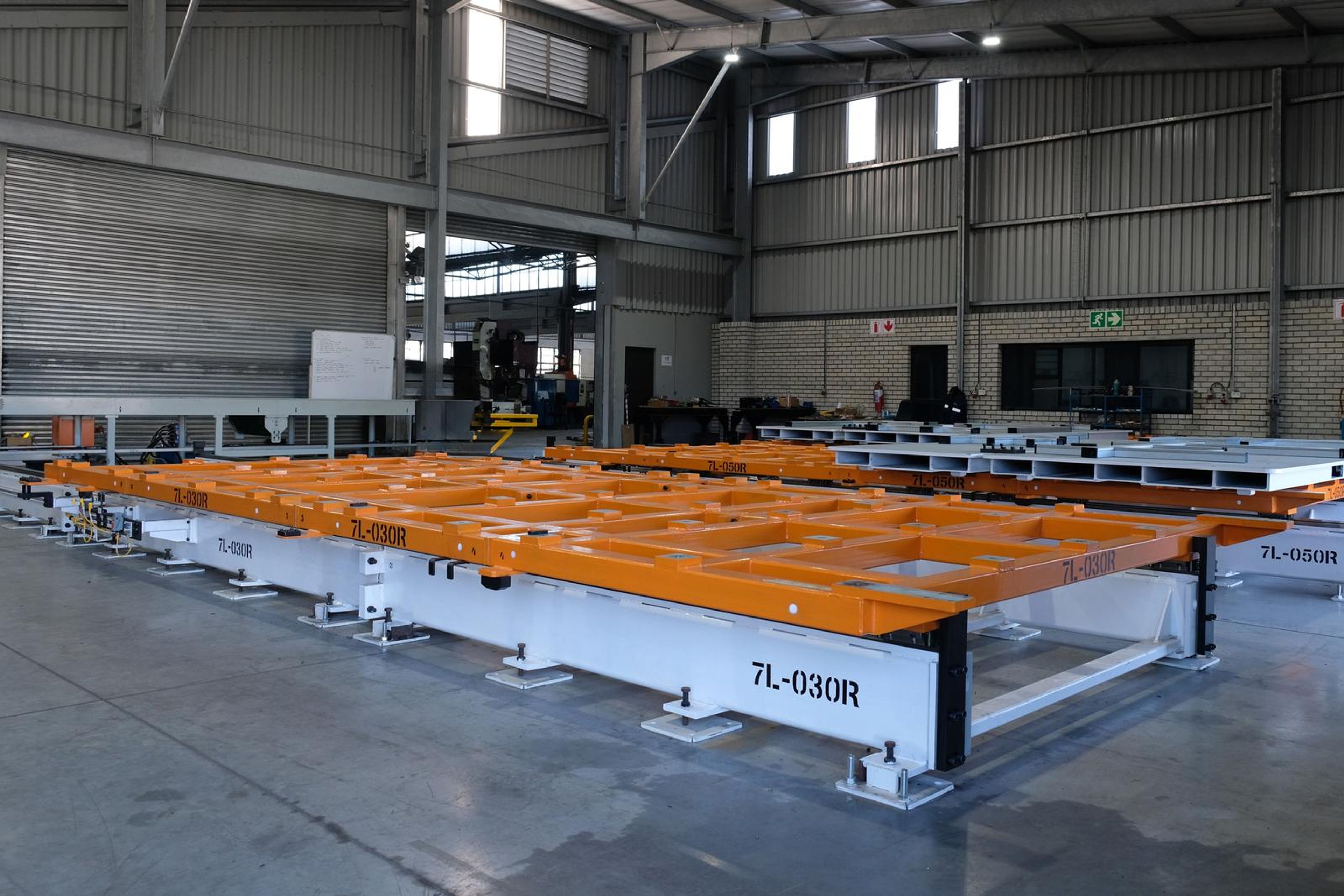 Wide view of the orange and white steel tool stencilled 7L-030R on the plant floor