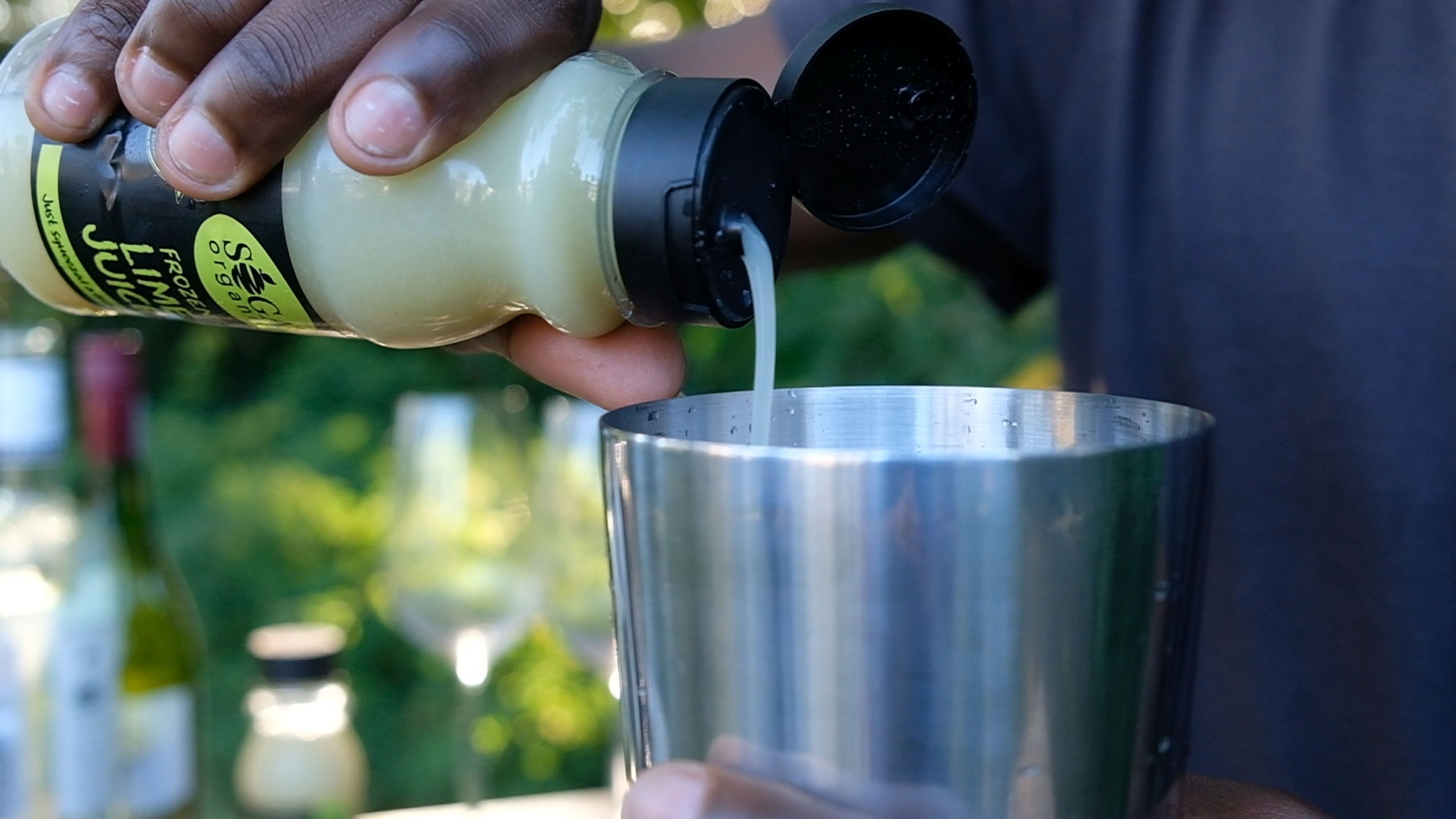 Lemon juice being poured from a SOGA bottle into a metal cocktail shaker