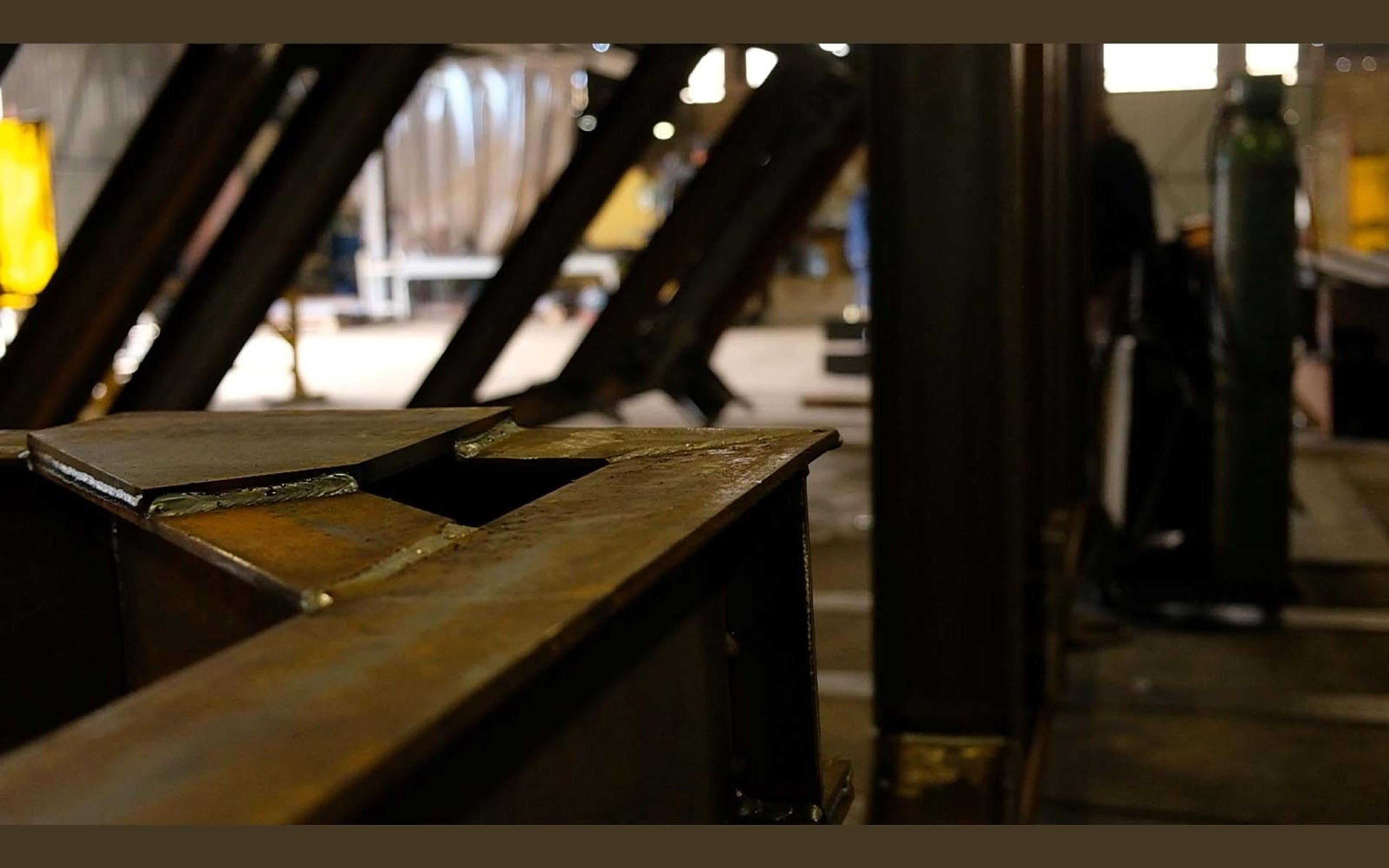 Fabrication bay with yellow welding screens and steel sections