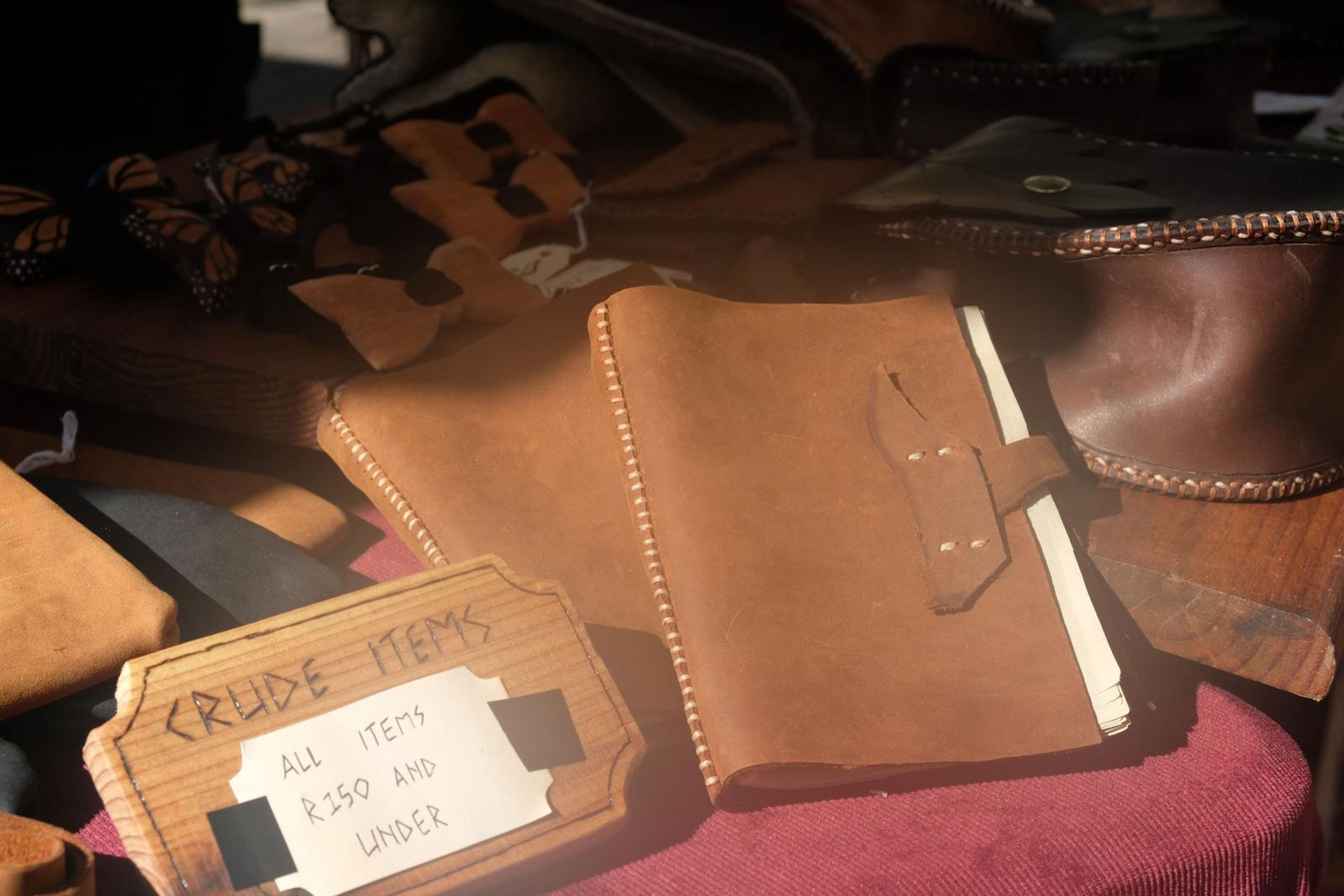Tan leather journal with stitched edges beside a Crude Items sign