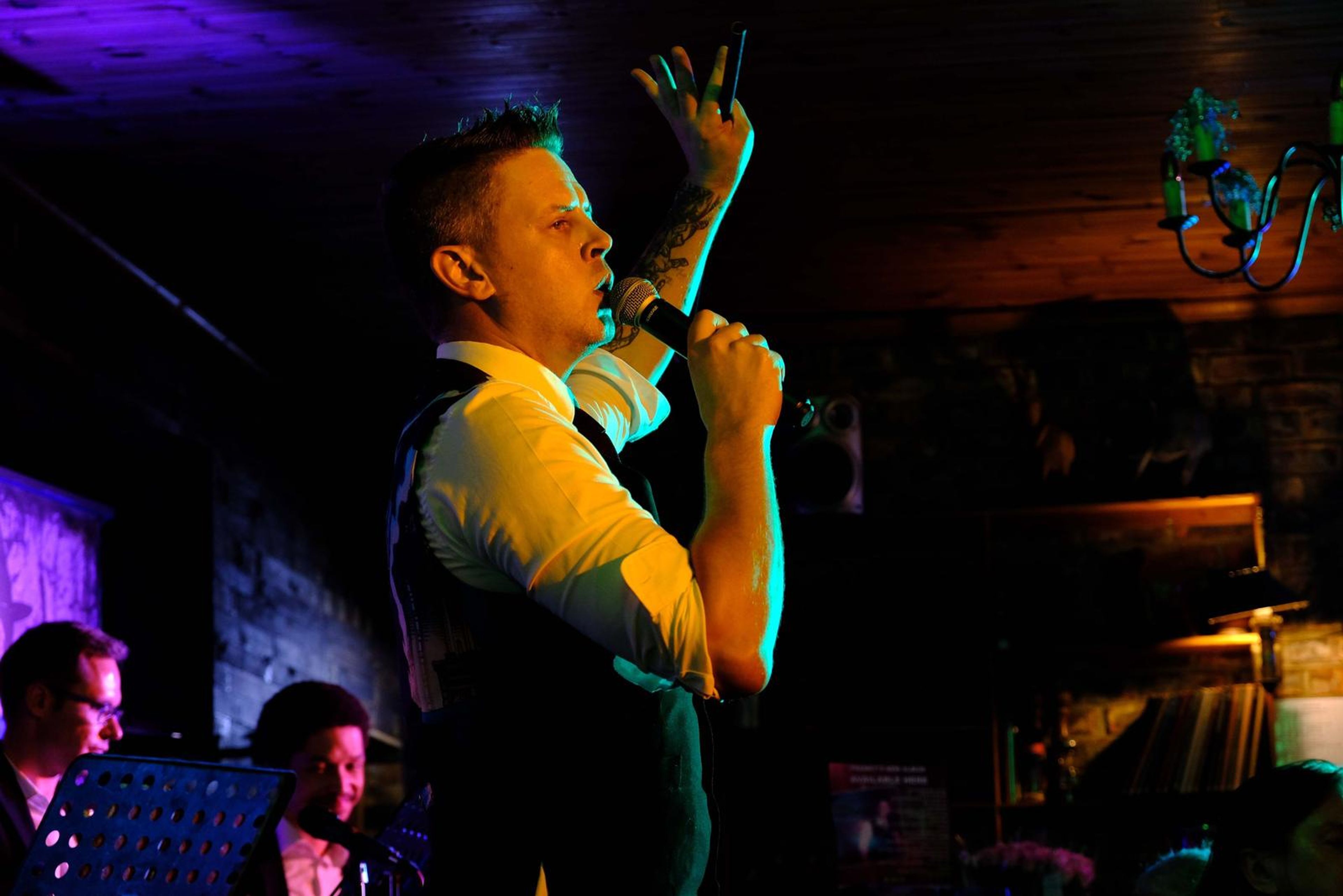 Singer in a waistcoat singing with his hand in the air
