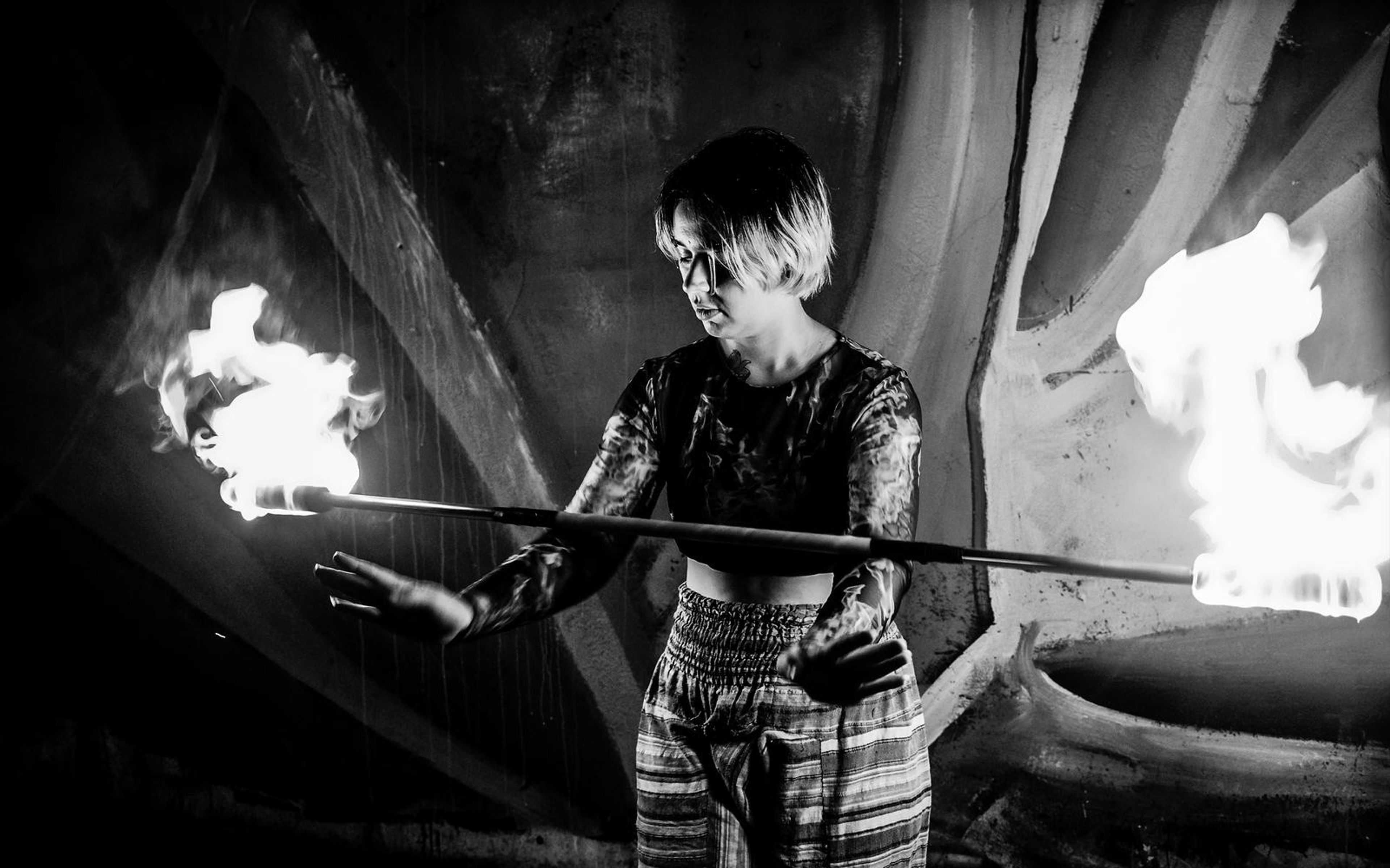 Black and white version of the performer with a flaming staff and bright flames at both ends