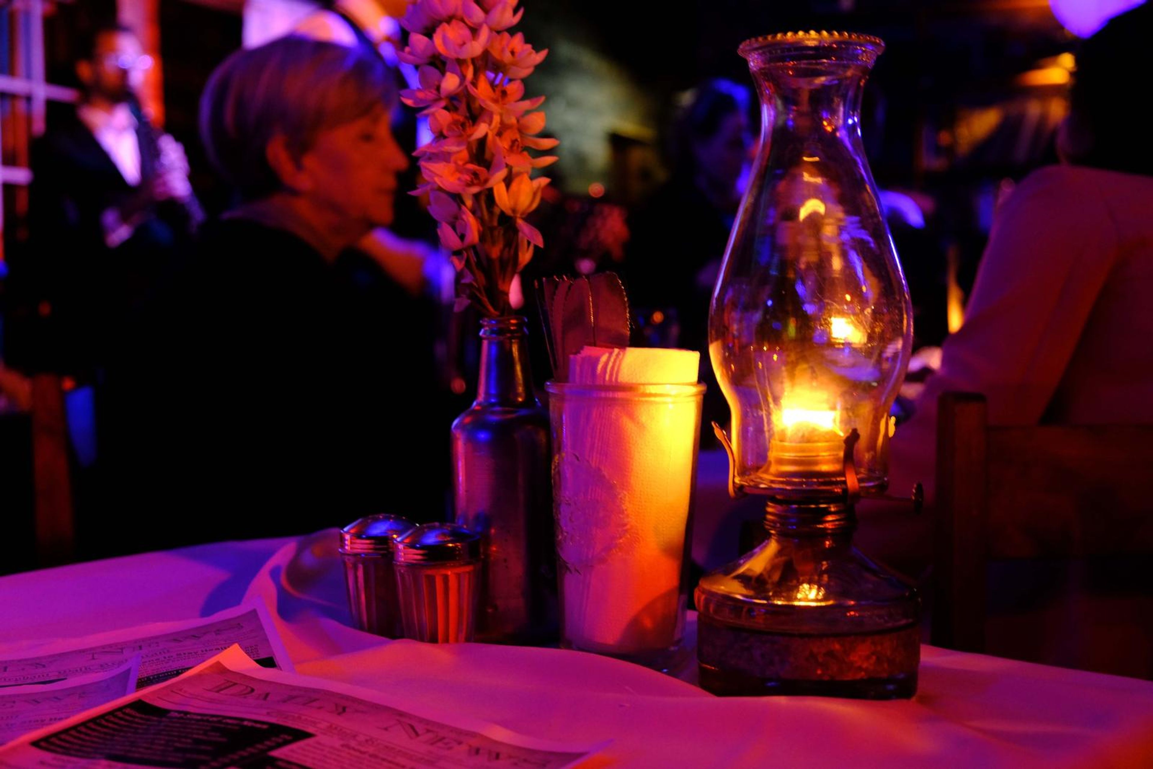 Candle-lit table with a lantern and flowers beside a guest