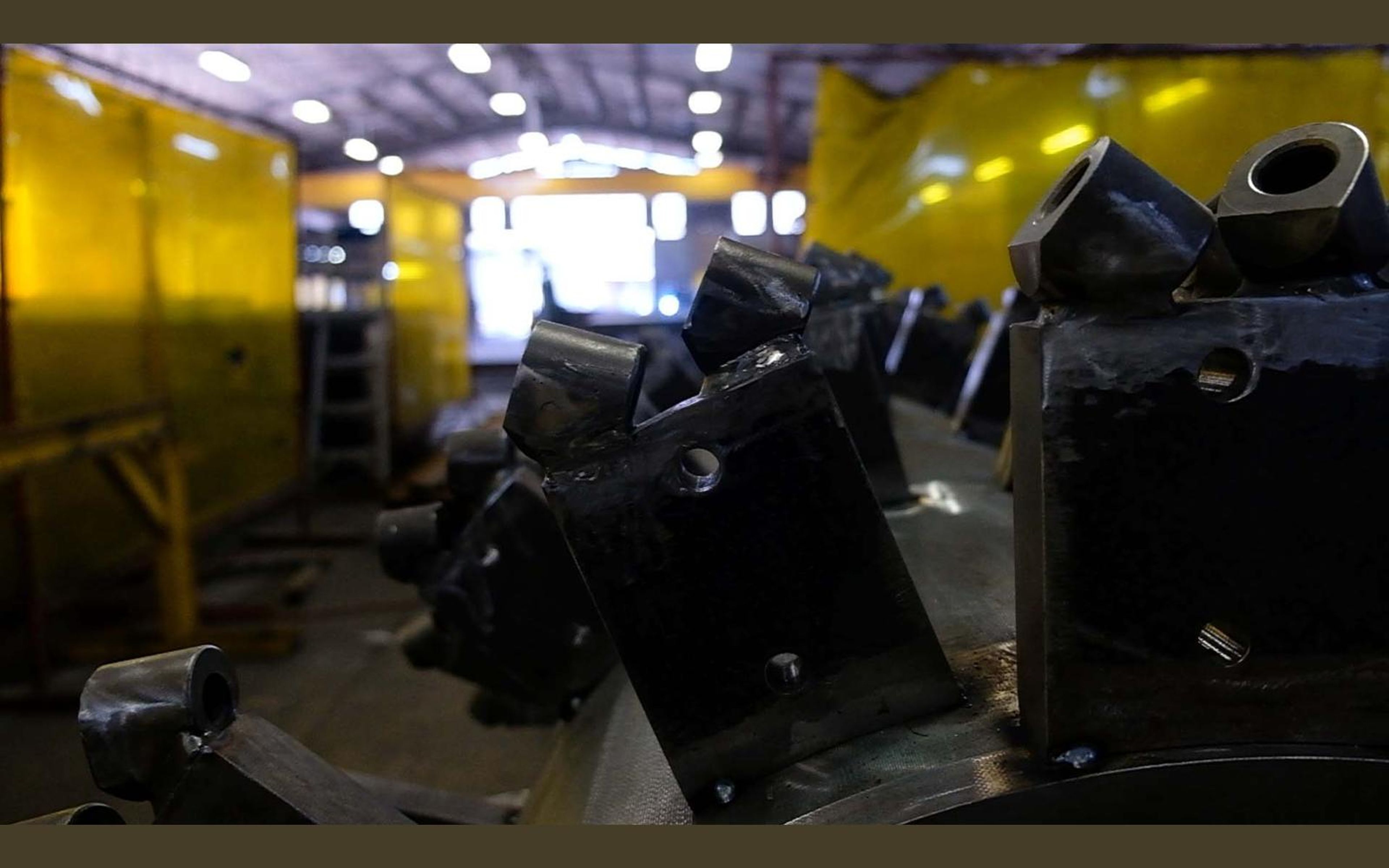Brackets arranged around a drum while a welder works