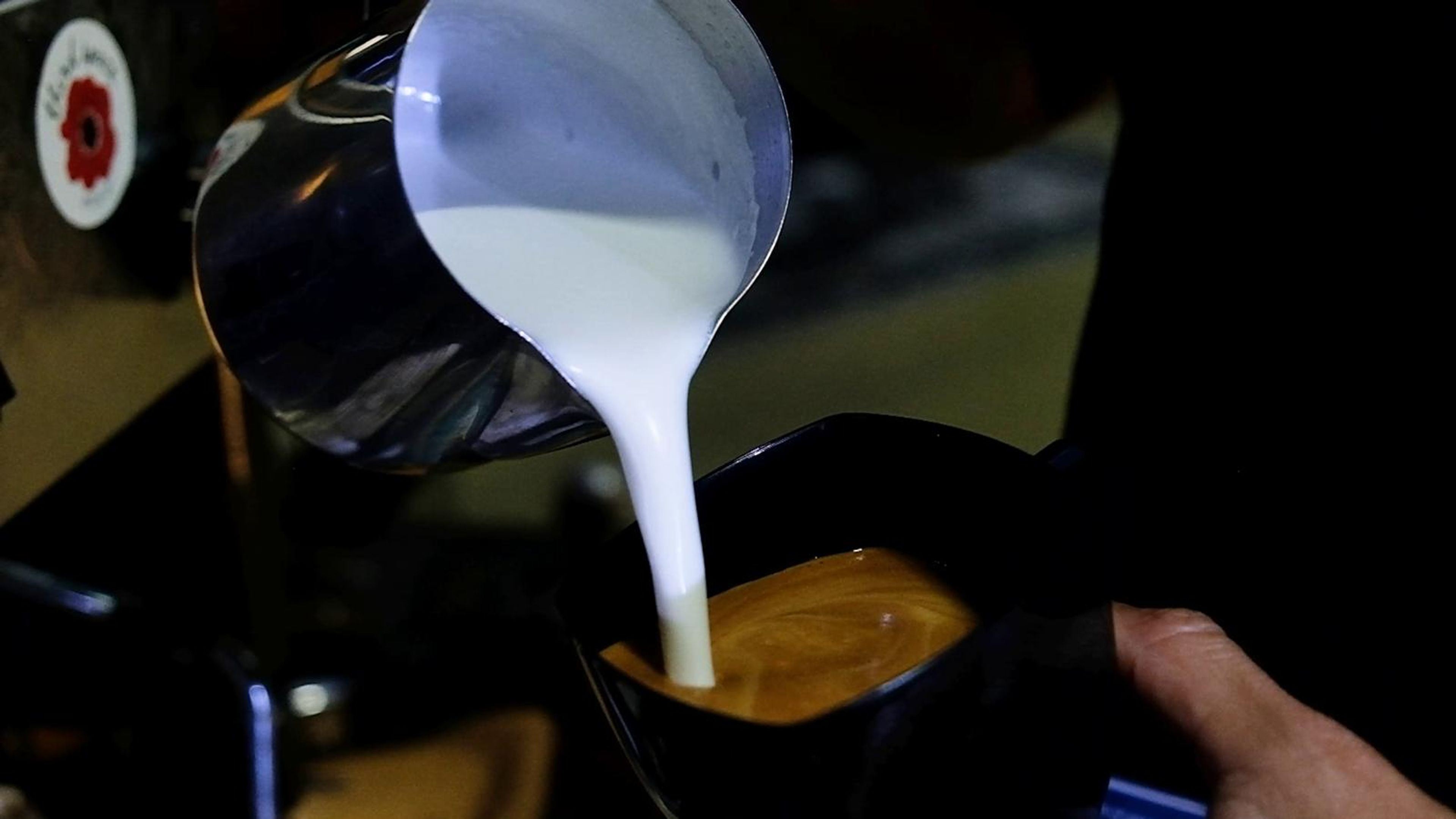 Milk being poured into a coffee cup