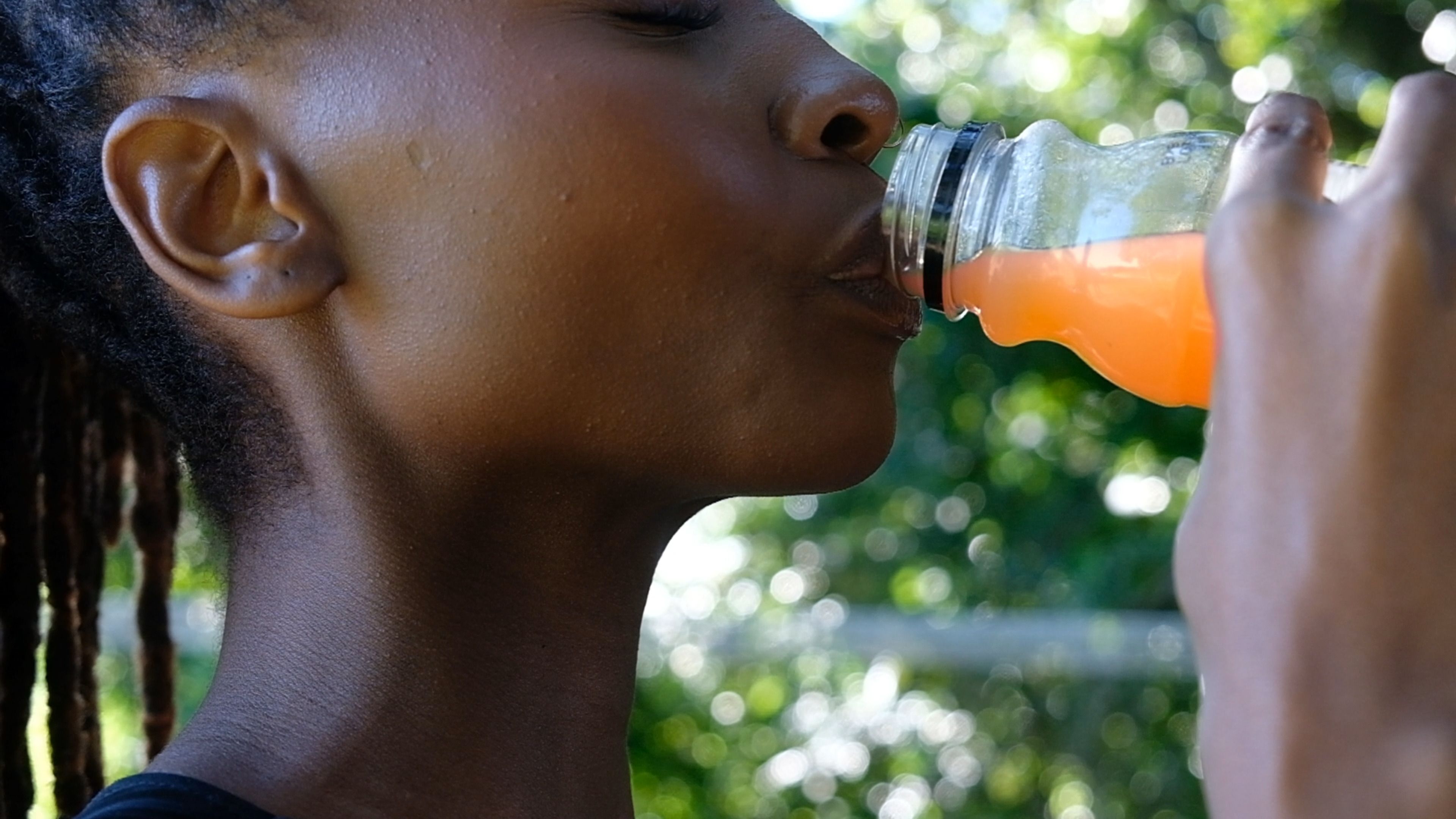 Close-up of a woman drinking ruby grapefruit juice from a bottle