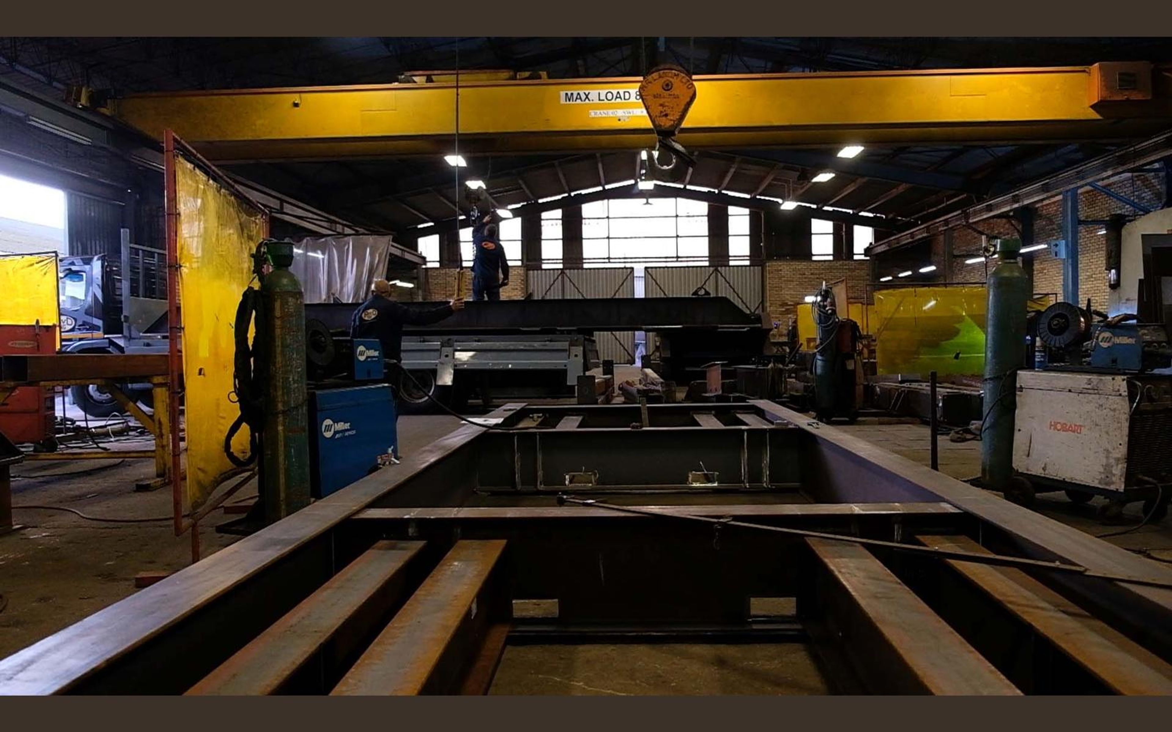 Fabrication bay with yellow welding screens and steel sections