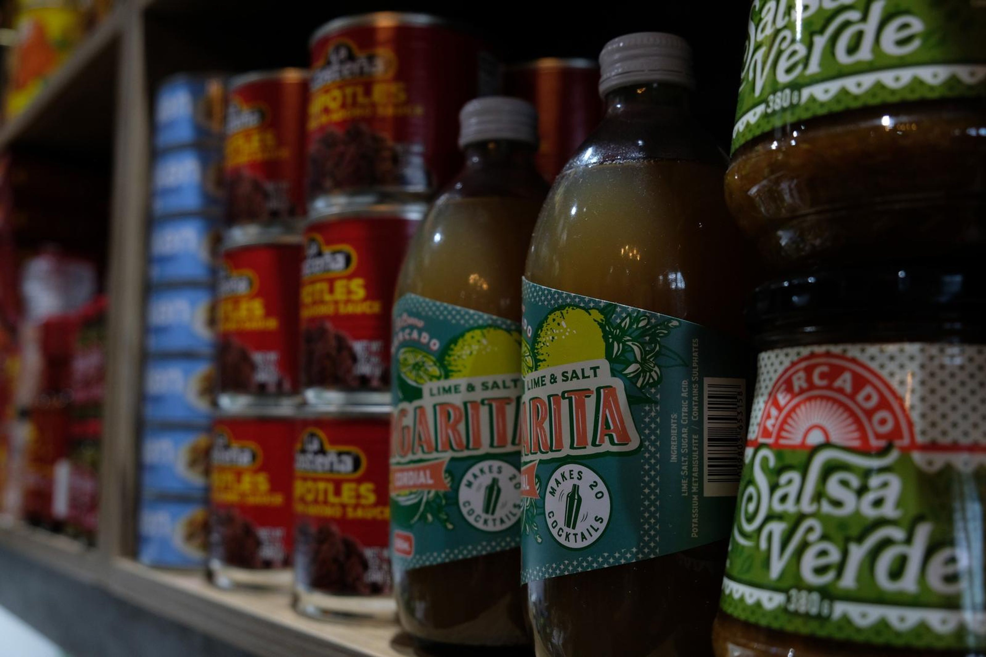 Tinned chipotle peppers and bottles of salsa verde on a shelf
