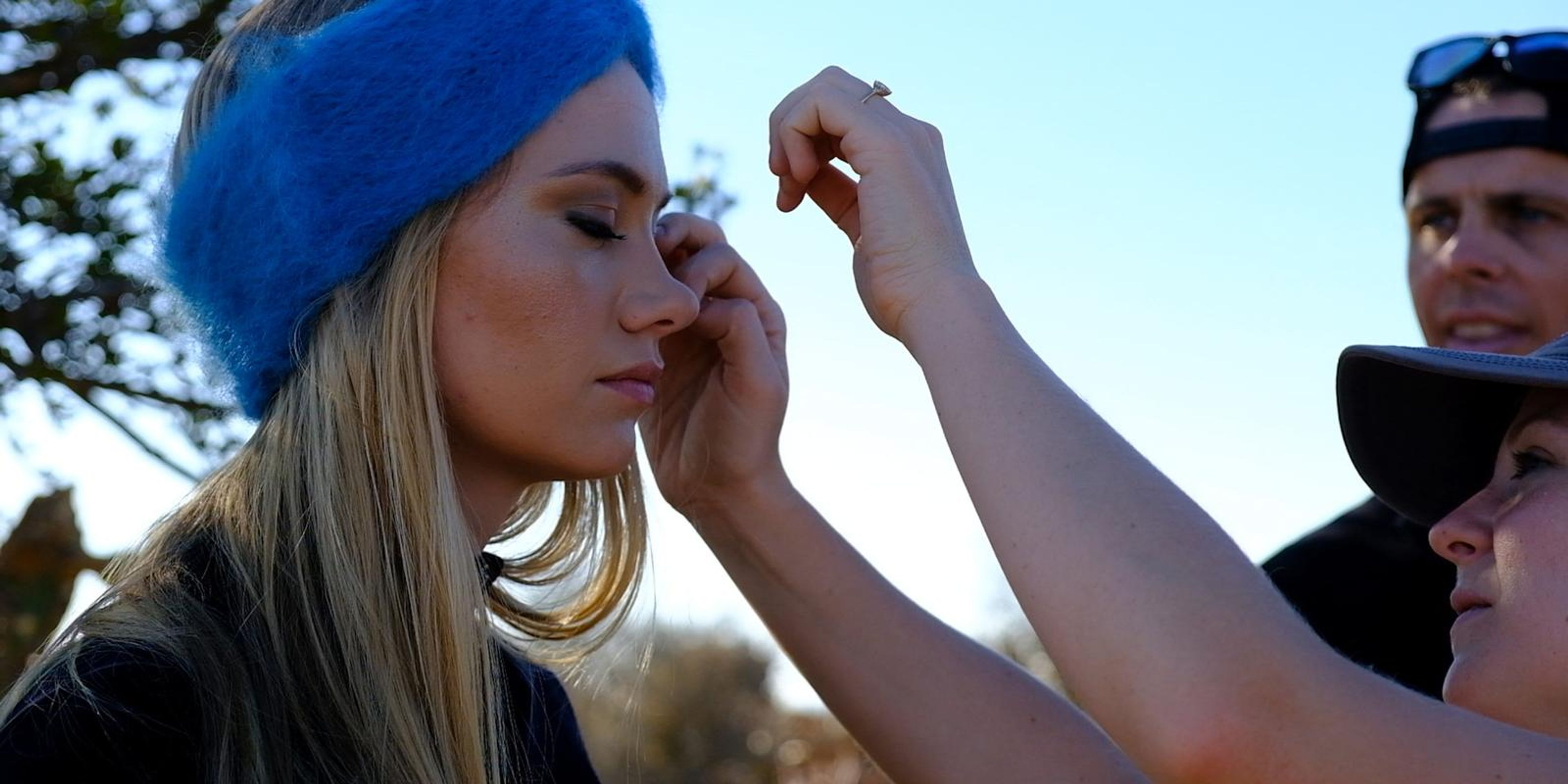 Make-up artist touching up the model's face as the crew looks on